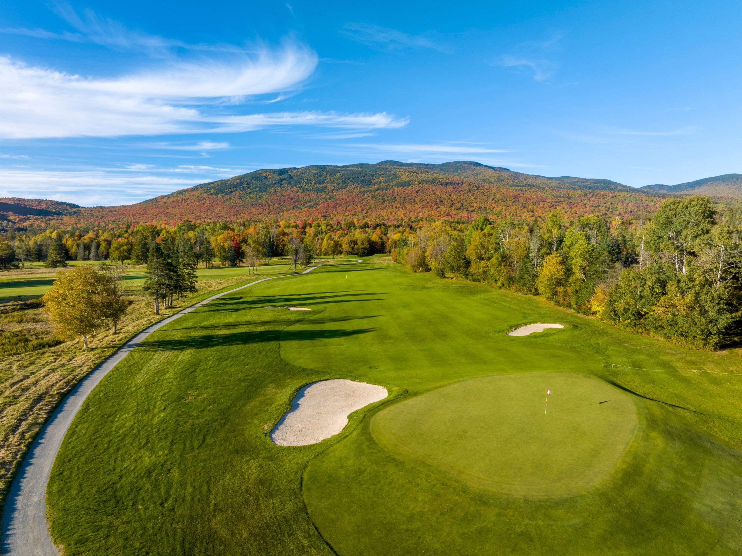 The golf course at Mount Washington Resort and Spa surrounded by a forest of trees in vibrant fall colours.