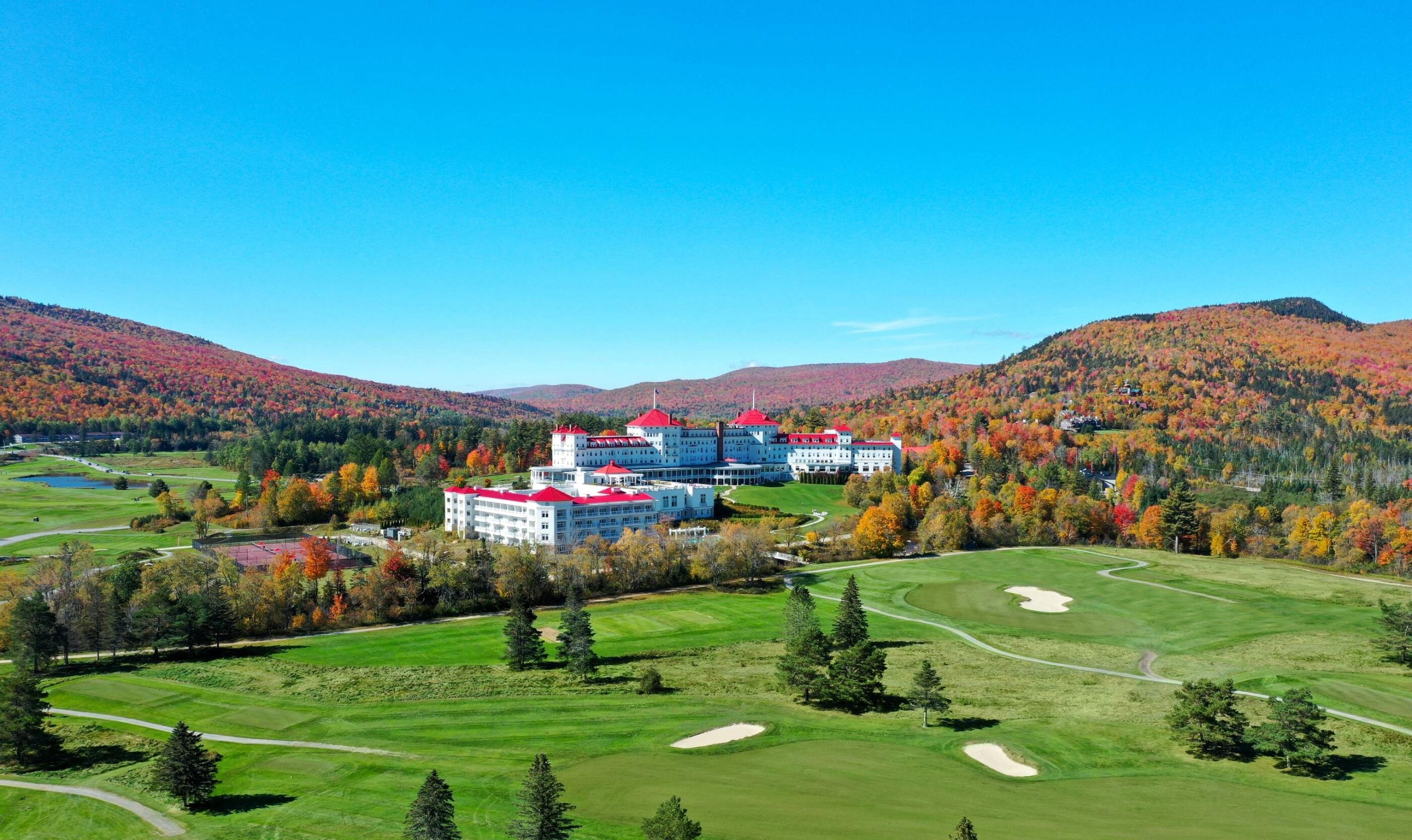 Mount Washington Resort and Spa sits nestled in a forest surrounded by trees with vibrant fall colors.