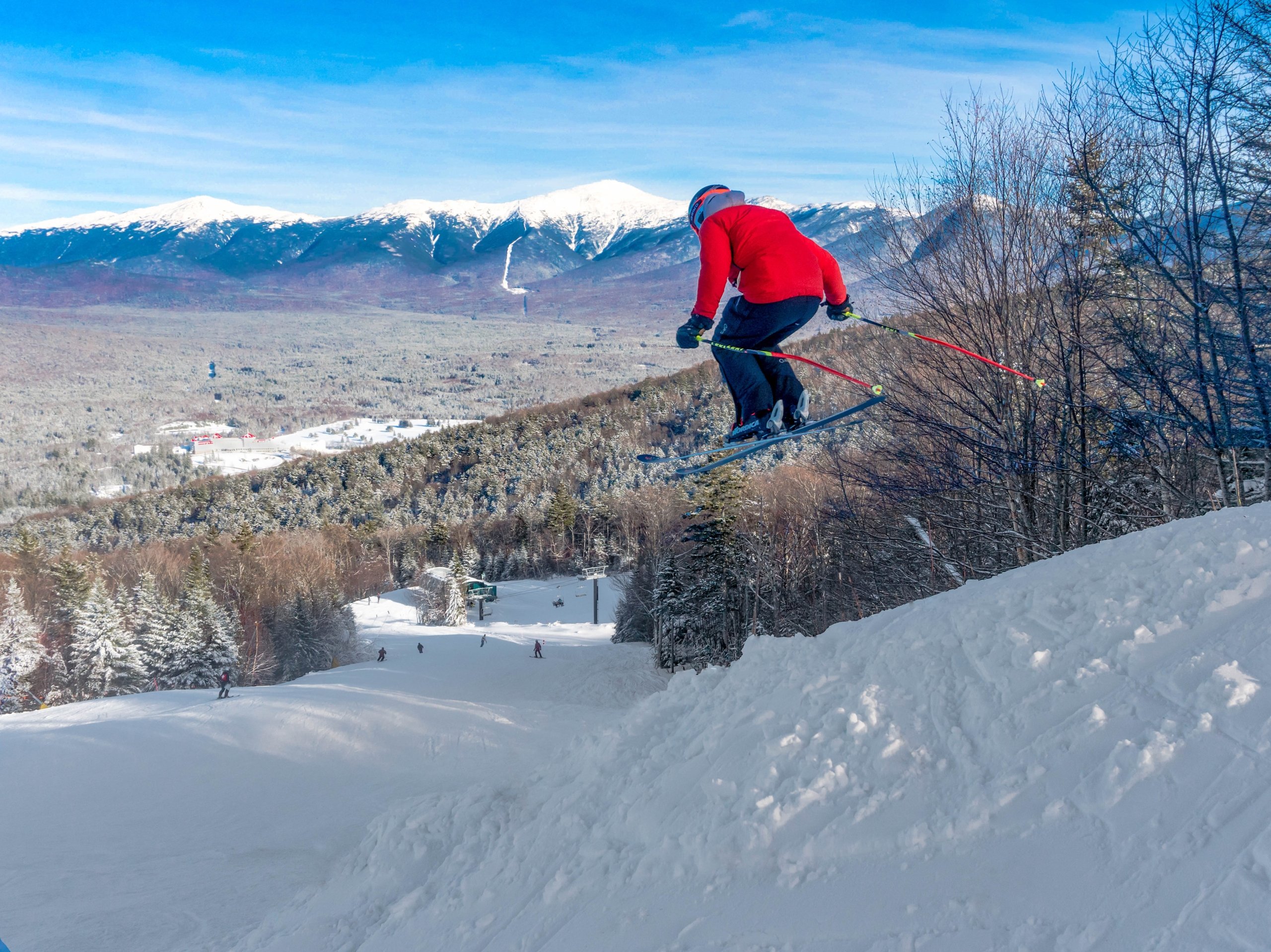 A skier performs a jump in the air while gliding down a snow-covered trail at Bretton Woods.