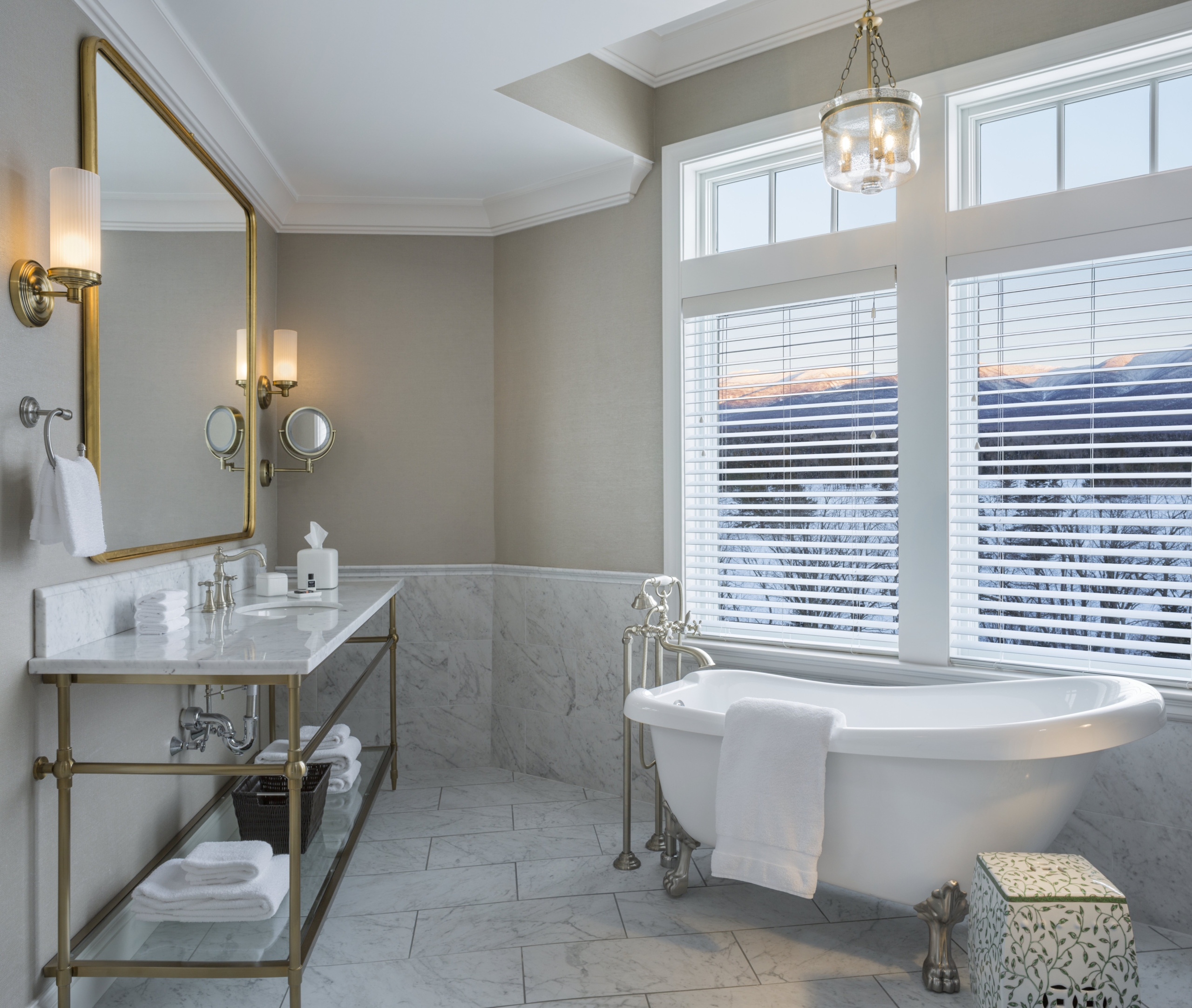 The bathroom in the Executive Presidential Suite at Mount Washington Resort and Spa features a freestanding white clawfoot bathtub beside large windows with views of snow-covered mountains.