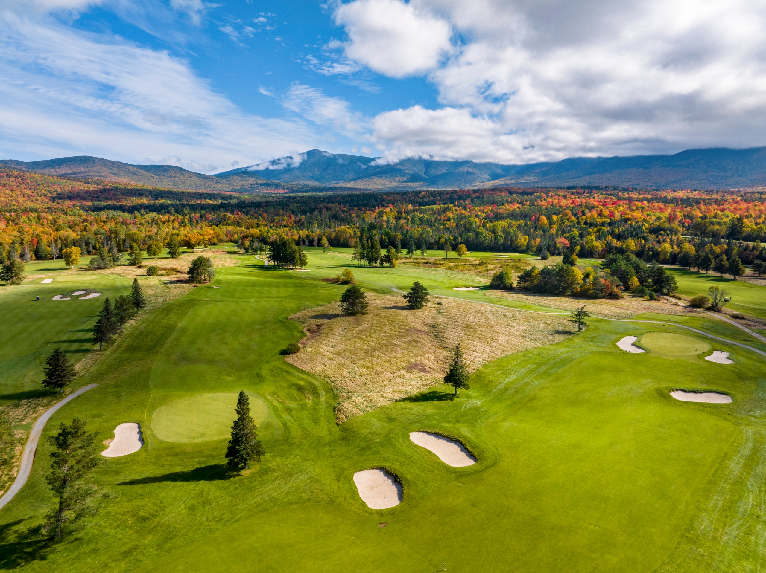 The golf course at Mount Washington Resort and Spa surrounded by a forest of trees in vibrant fall colours.