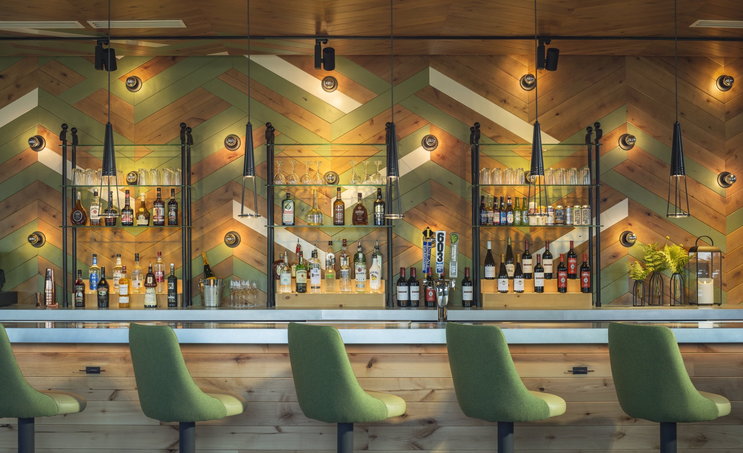 Green bar stools lined up at the stocked bar at Switchback Grille.