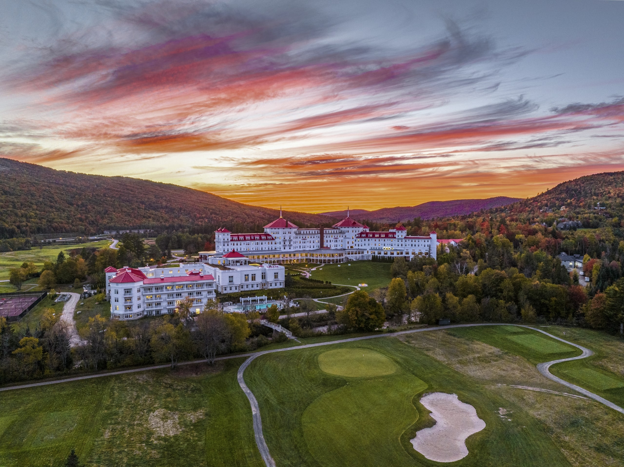 Mount Washington Resort and Spa sits nestled among rolling hills and surrounded by autumn trees at sunset.