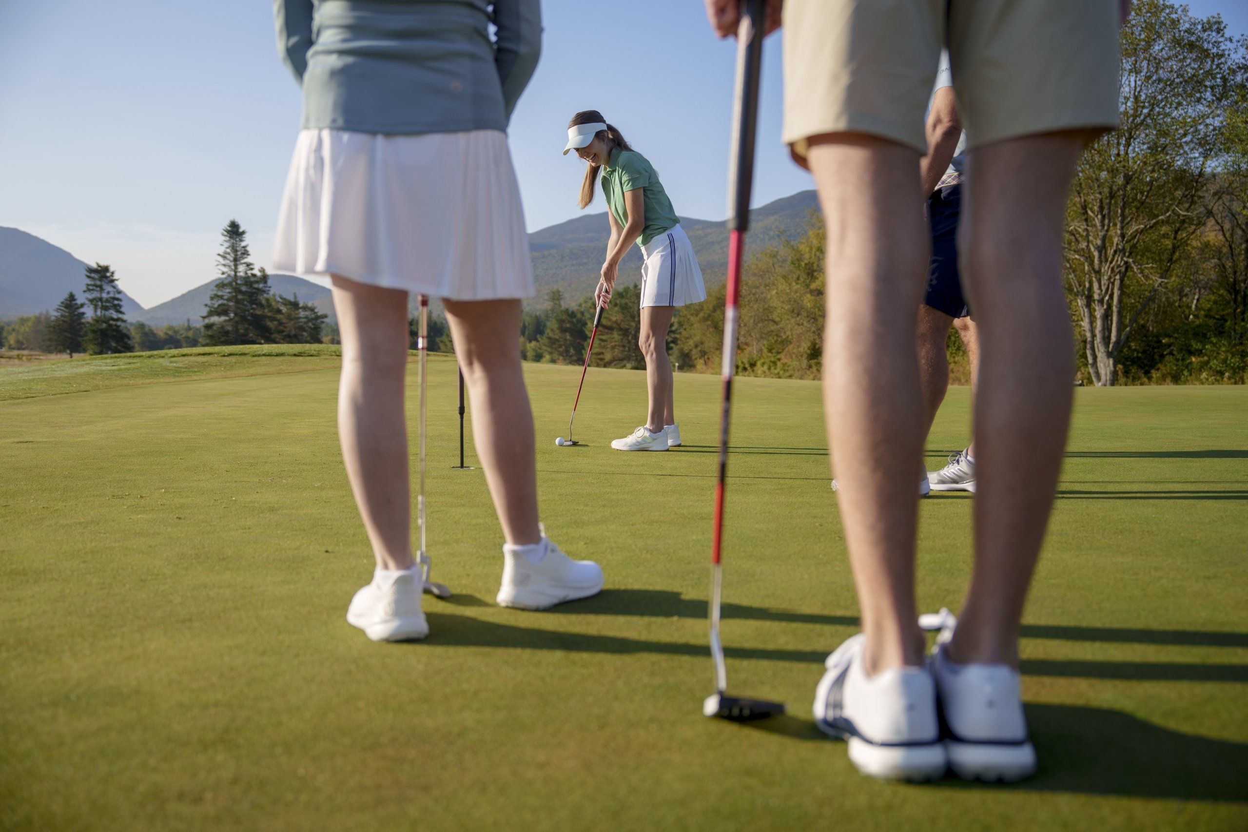 A woman prepares to putt on a golf green while three other players watch nearby at Mount Washington Resort and Spa.
