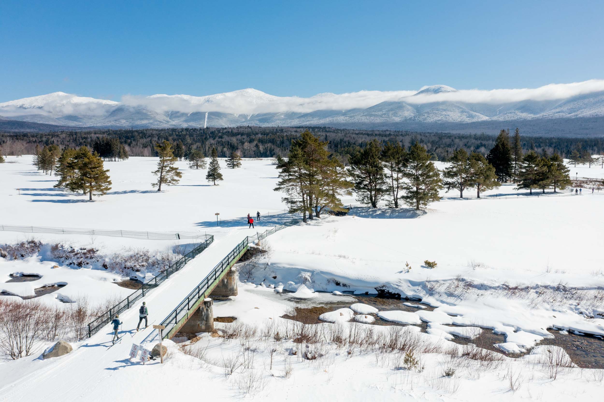 A group of skiers cross a snowy bridge at Bretton Woods.