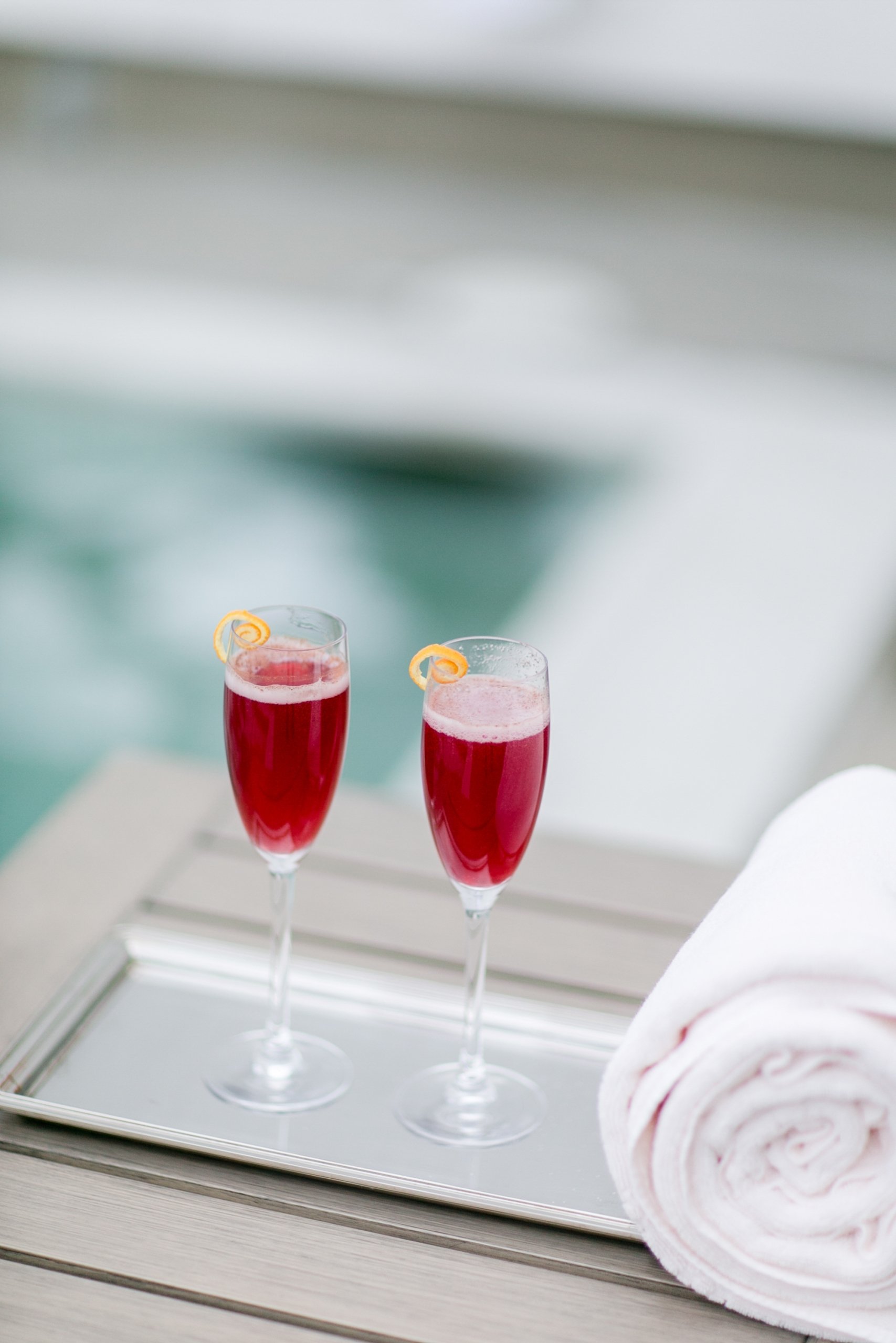 Two festive drinks in champagne flutes sit on a tray beside a white rolled towel at the spa at Mount Washington Resort and Spa.