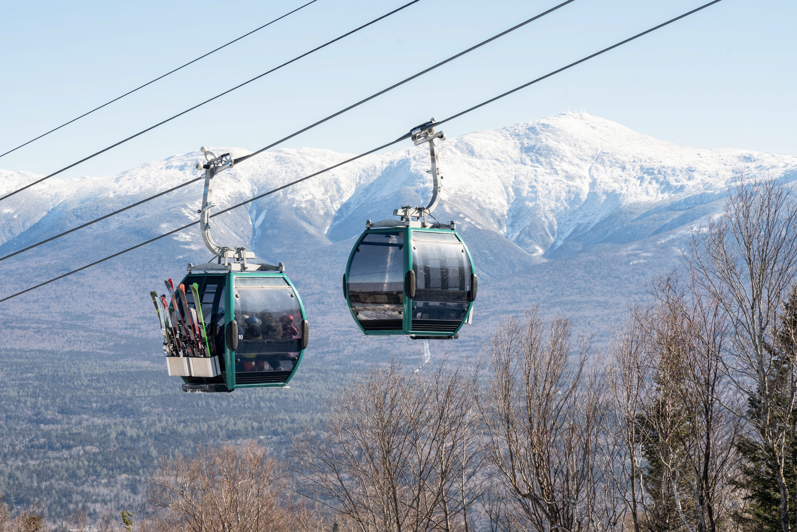 Two ski gondolas carry riders up a snowy mountain at Bretton Woods.