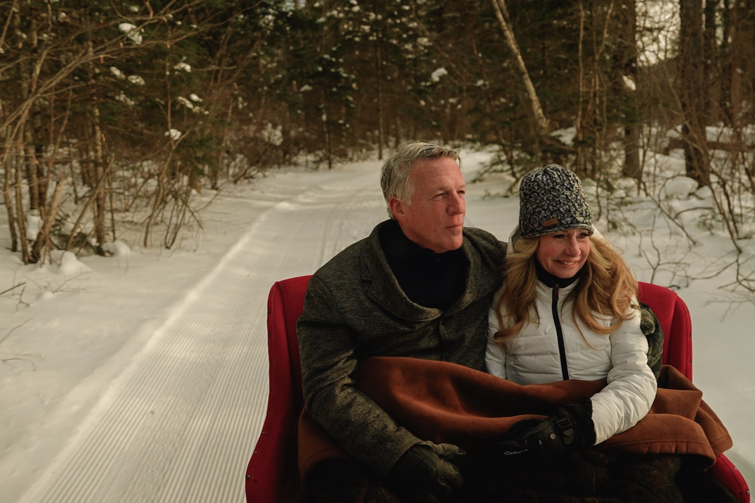 A man and woman take a ride on a sleigh through a snowy trail at Mount Washington Resort and Spa.
