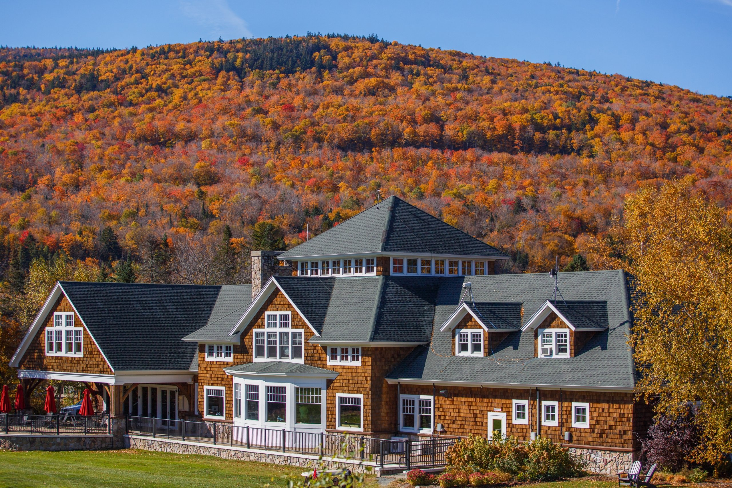 A large lodge-style building sits before a hillside covered in vibrant autumn foliage at Mount Washington Resort and Spa.