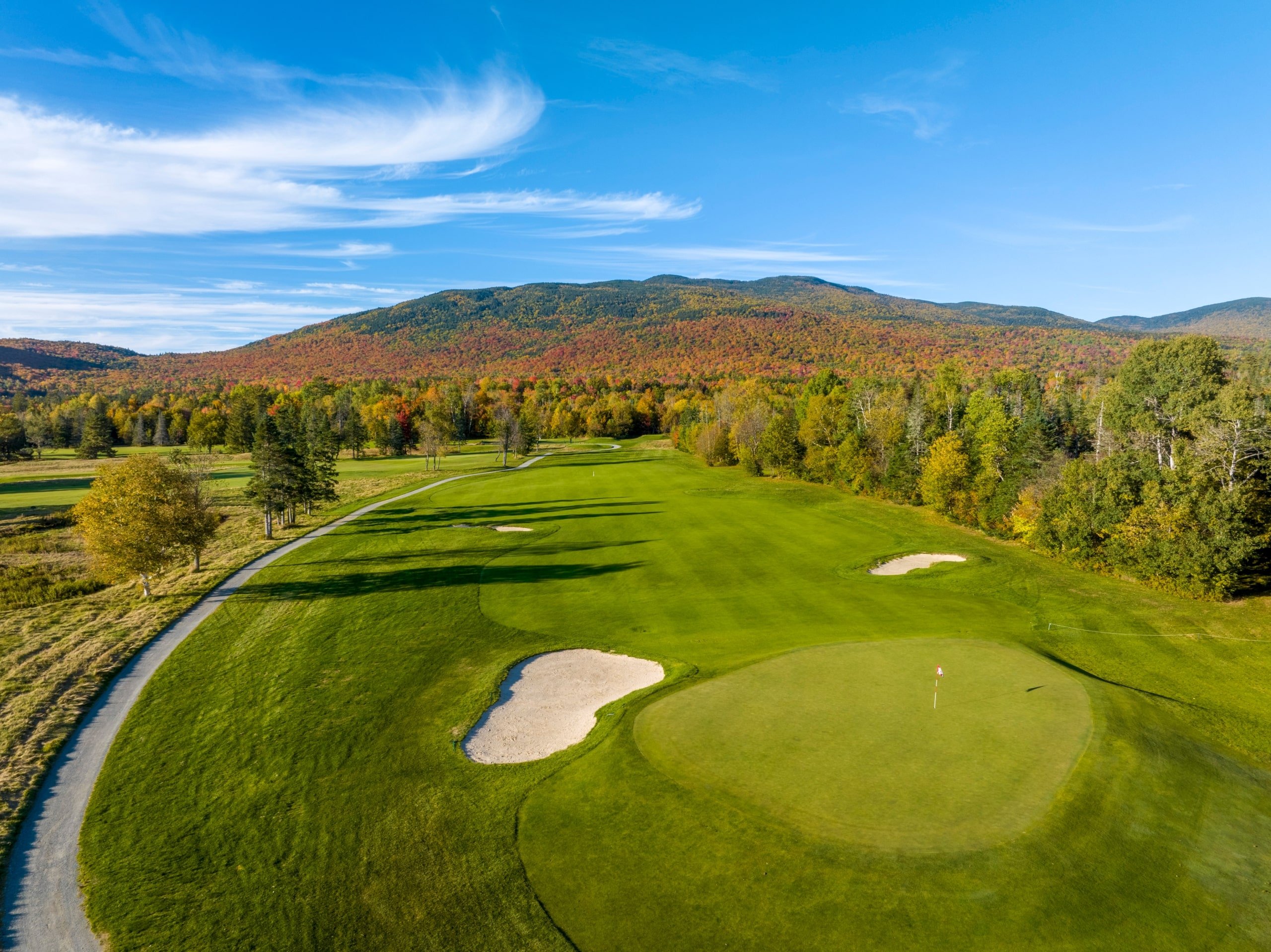 The golf course at Mount Washington Resort and Spa surrounded by a forest of trees in vibrant fall colours.