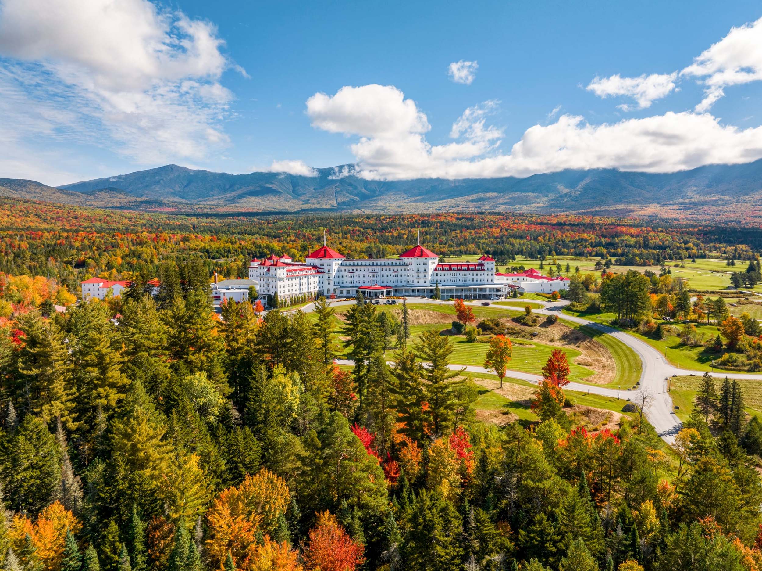 Mount Washington Resort and Spa sits at the bottom of a mountain surrounded by a lush forest of trees in vibrant fall colours.