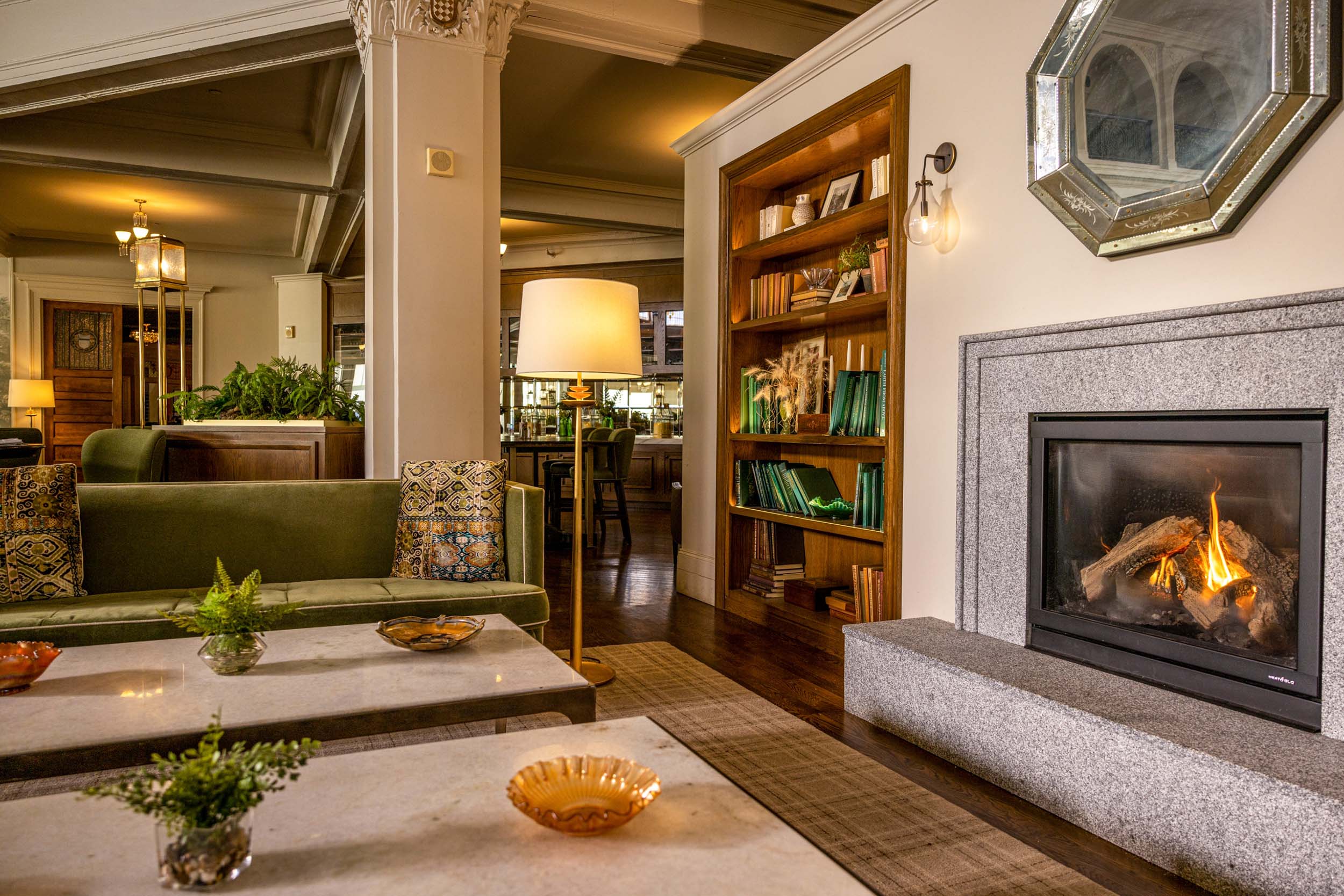 Elegant lounge area with a cozy fireplace, green sofa, and bookshelves creating a warm, inviting atmosphere at Mount Washington Resort and Spa.