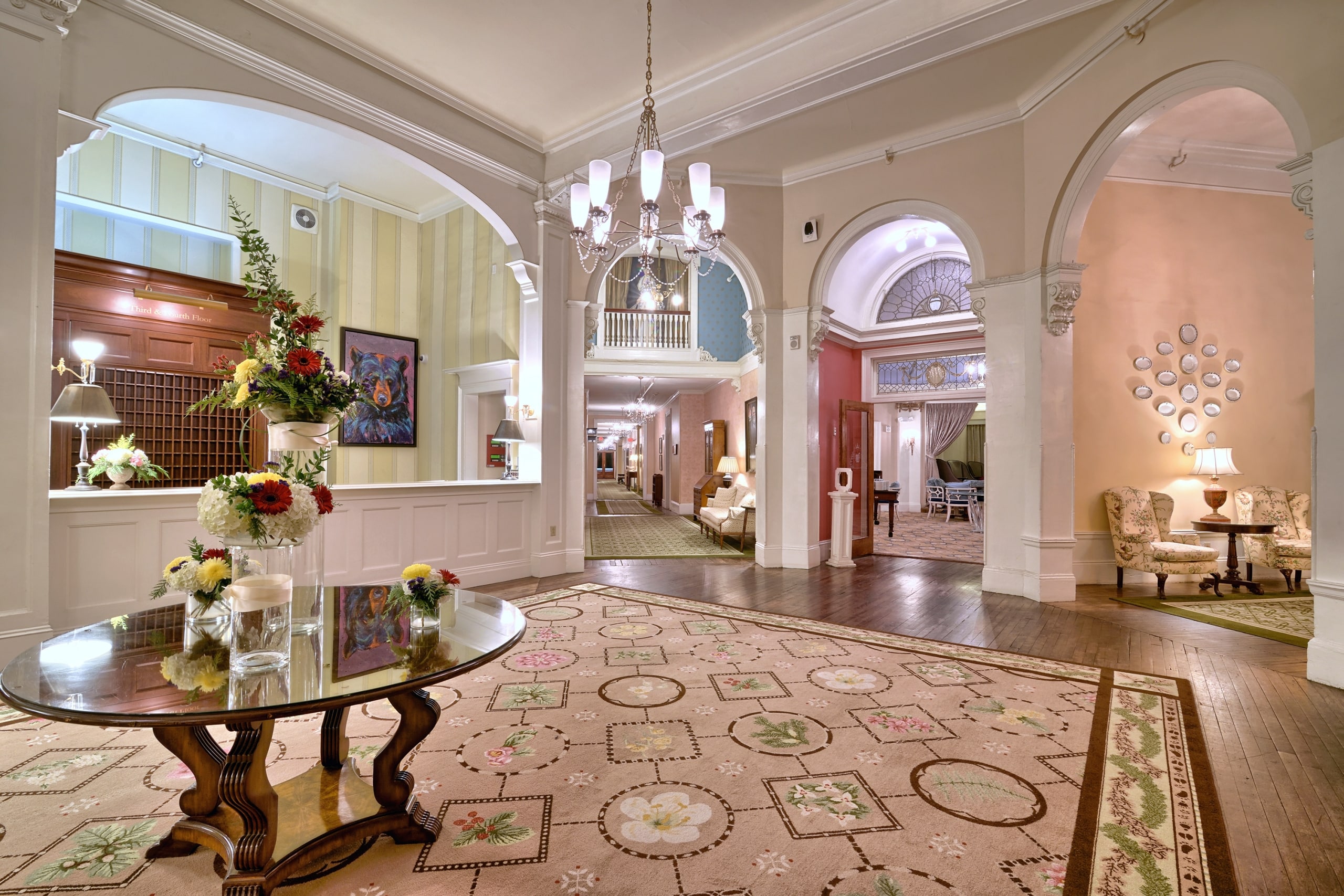 The elegant hotel lobby at Mount Washington Resort and Spa features arched doorways, a chandelier, and a floral-patterned carpet.