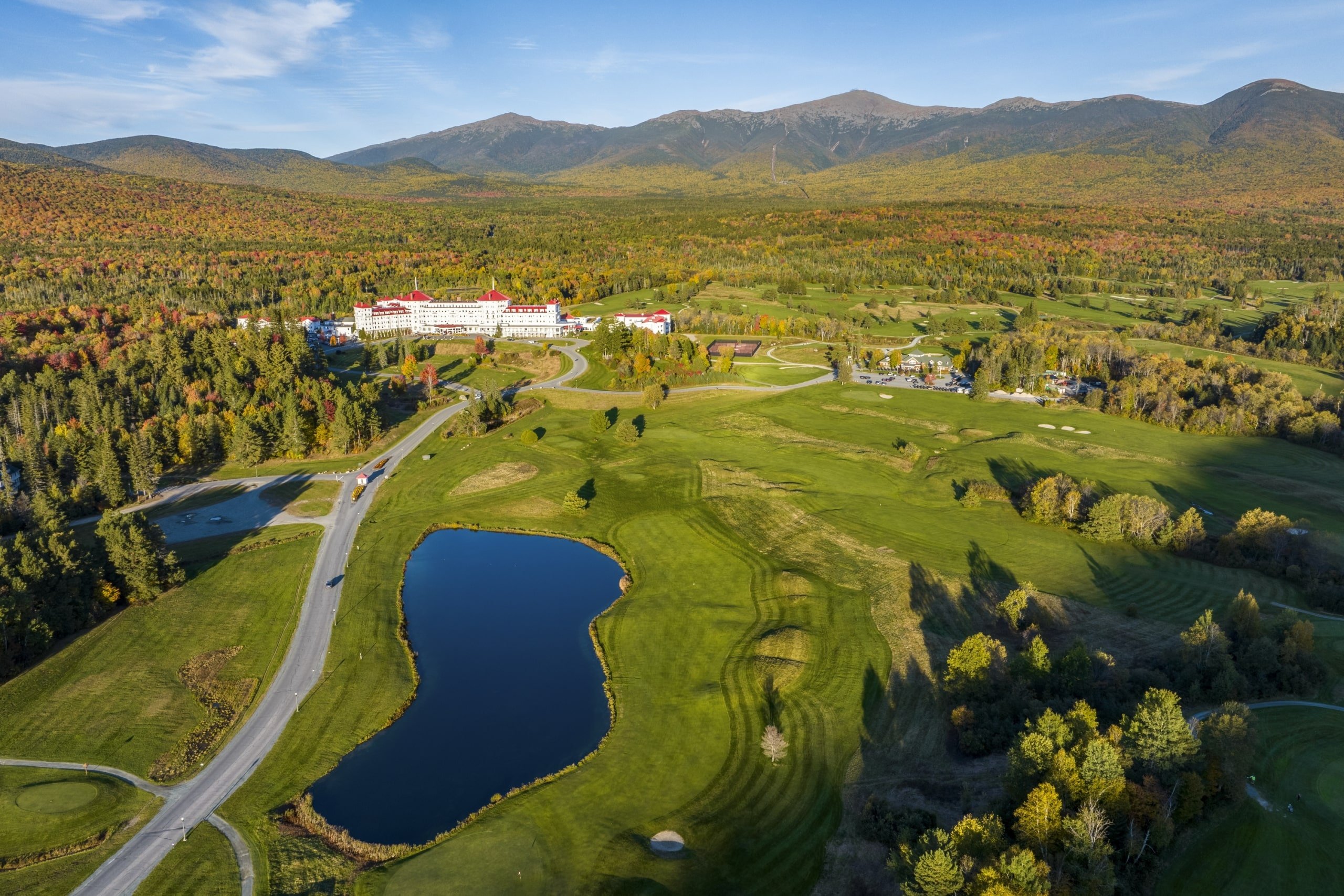 A long winding road leads to Mount Washington Resort and Spa sitting in the middle of a lush green landscape.