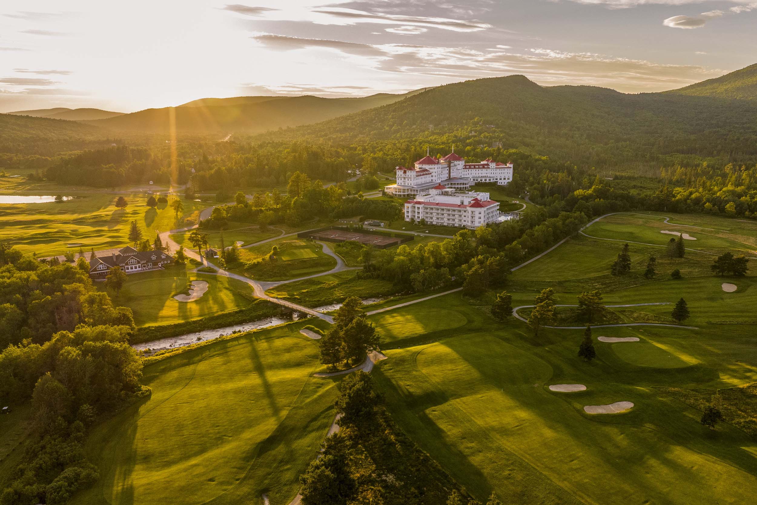 Mount Washington Resort and Spa stands amid lush green hills and a sprawling golf course, bathed in the golden light of sunset.
