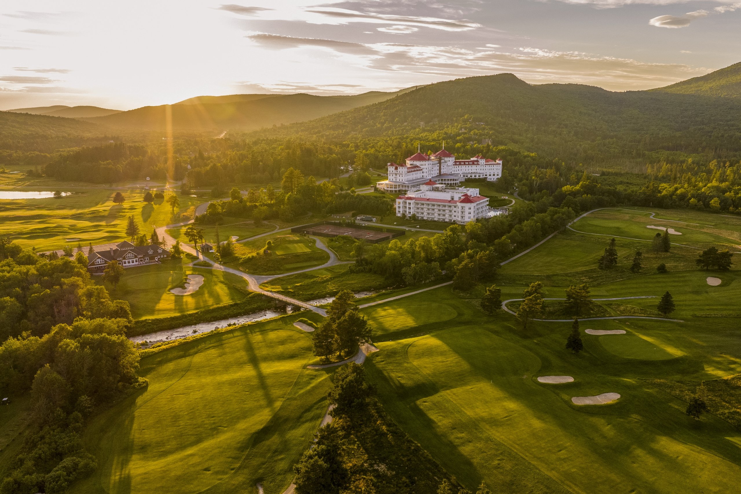 Mount Washington Resort and Spa stands amid lush green hills and a sprawling golf course, bathed in the golden light of sunset.