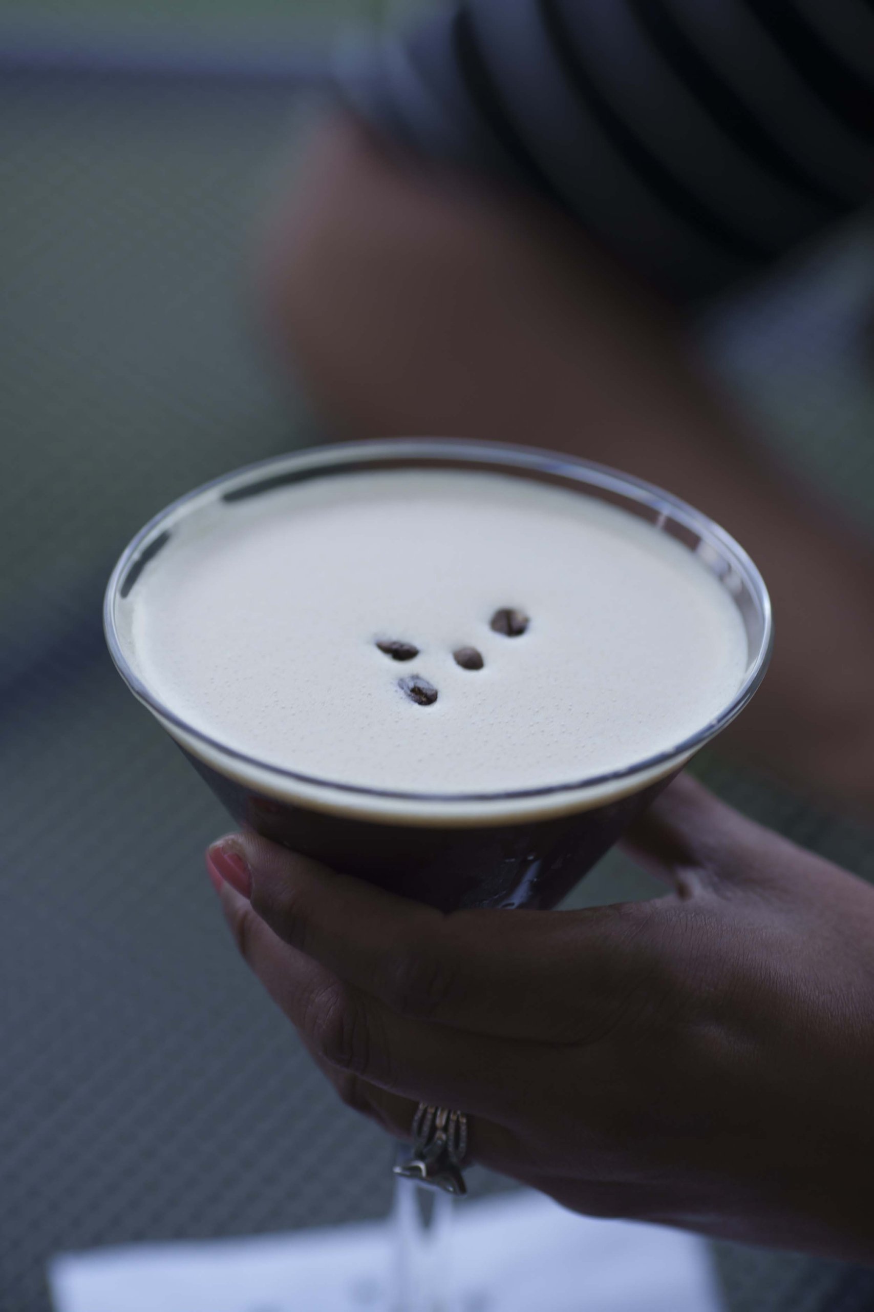 An espresso martini held in a hand.