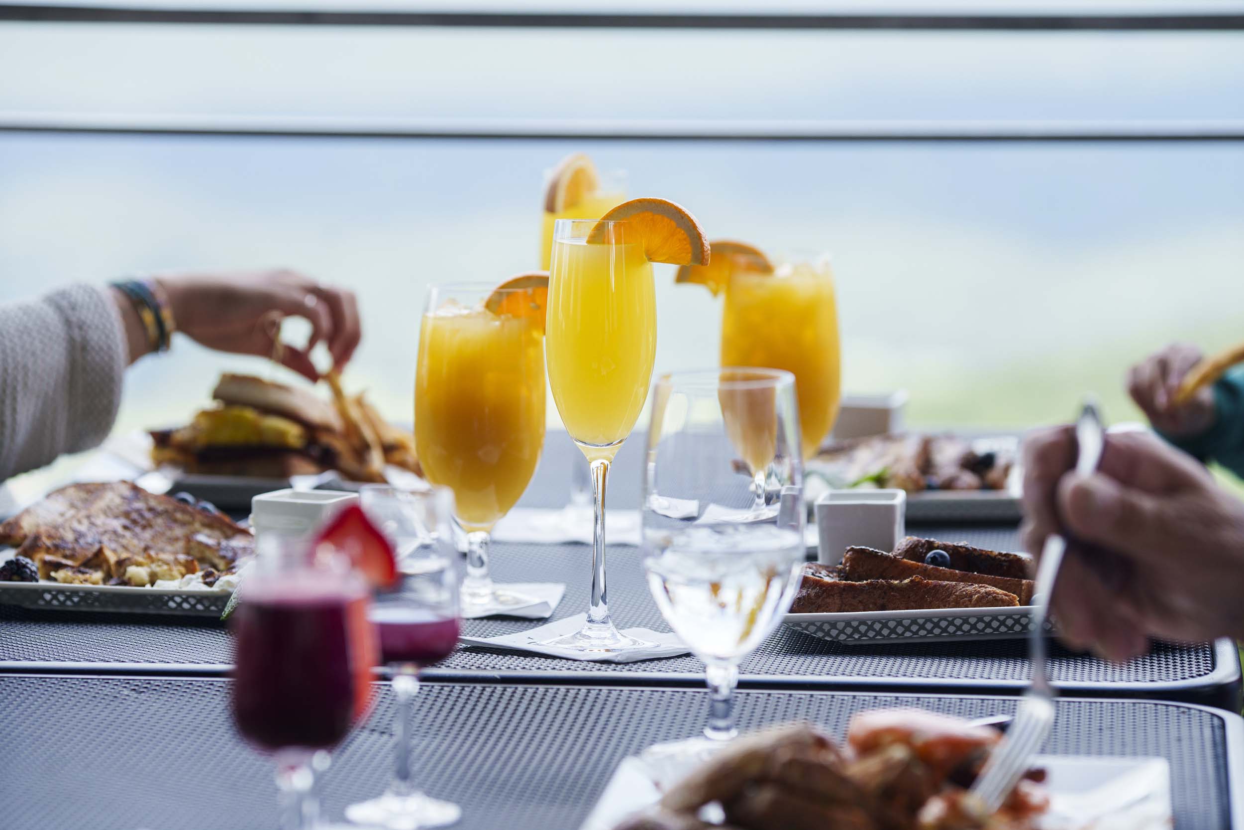 A dining table with breakfast served including mimosas.