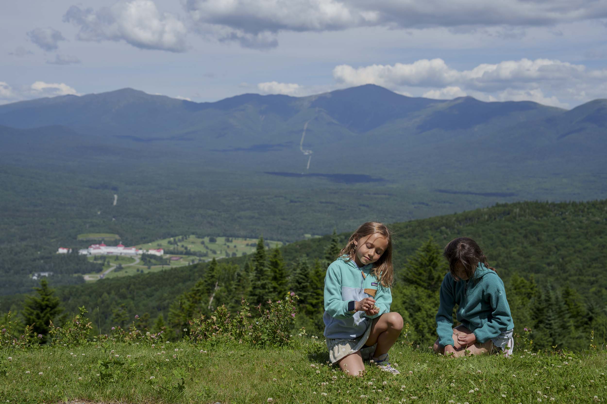 A close-up of two girls relax at the mountain top off hiking trails on Mount Washington.