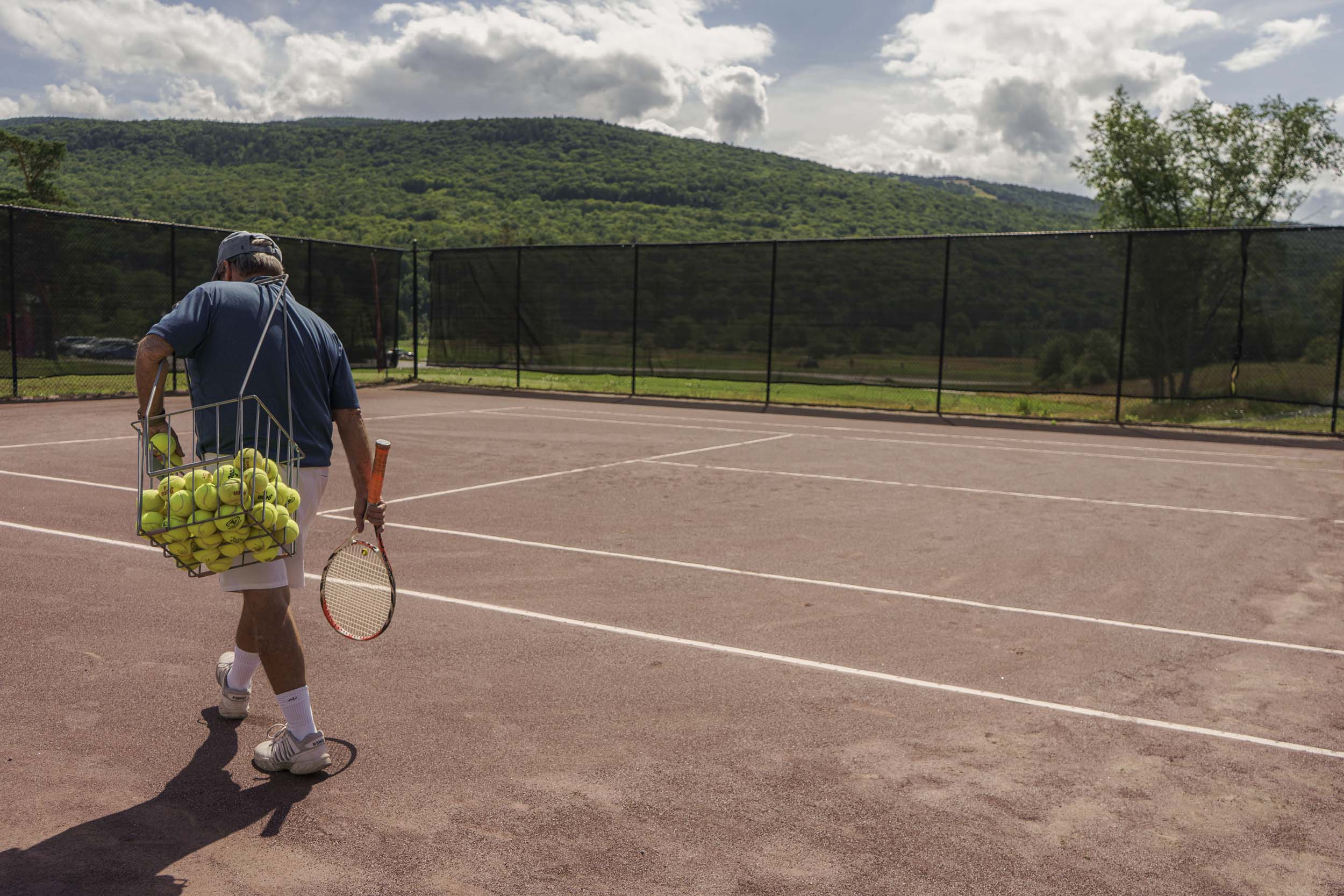 A man walks onto the tennis courts at OMNI Mount Washington Resort and Spa