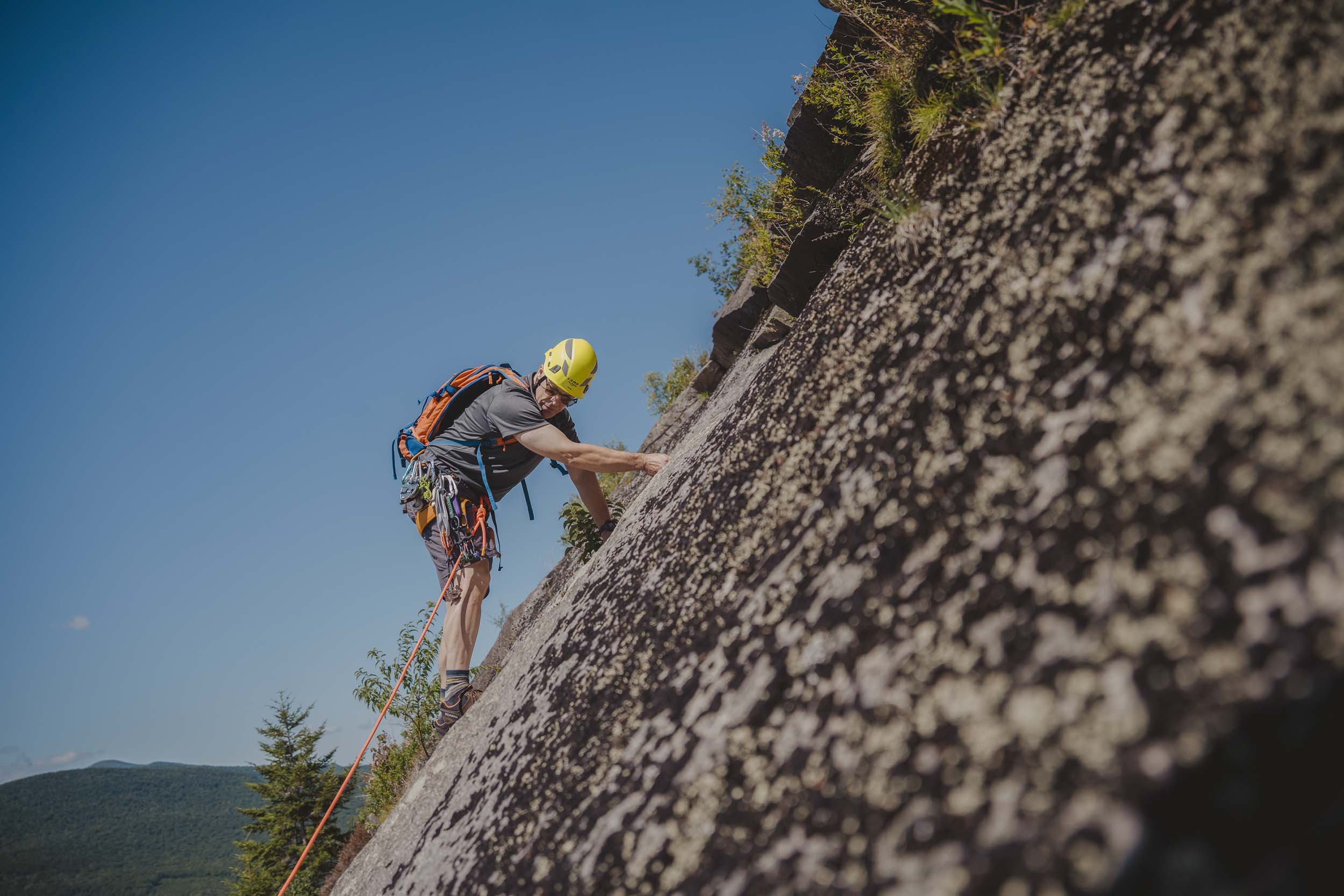 A rock climber looks down as they ascend the West Wall at Bretton Woods