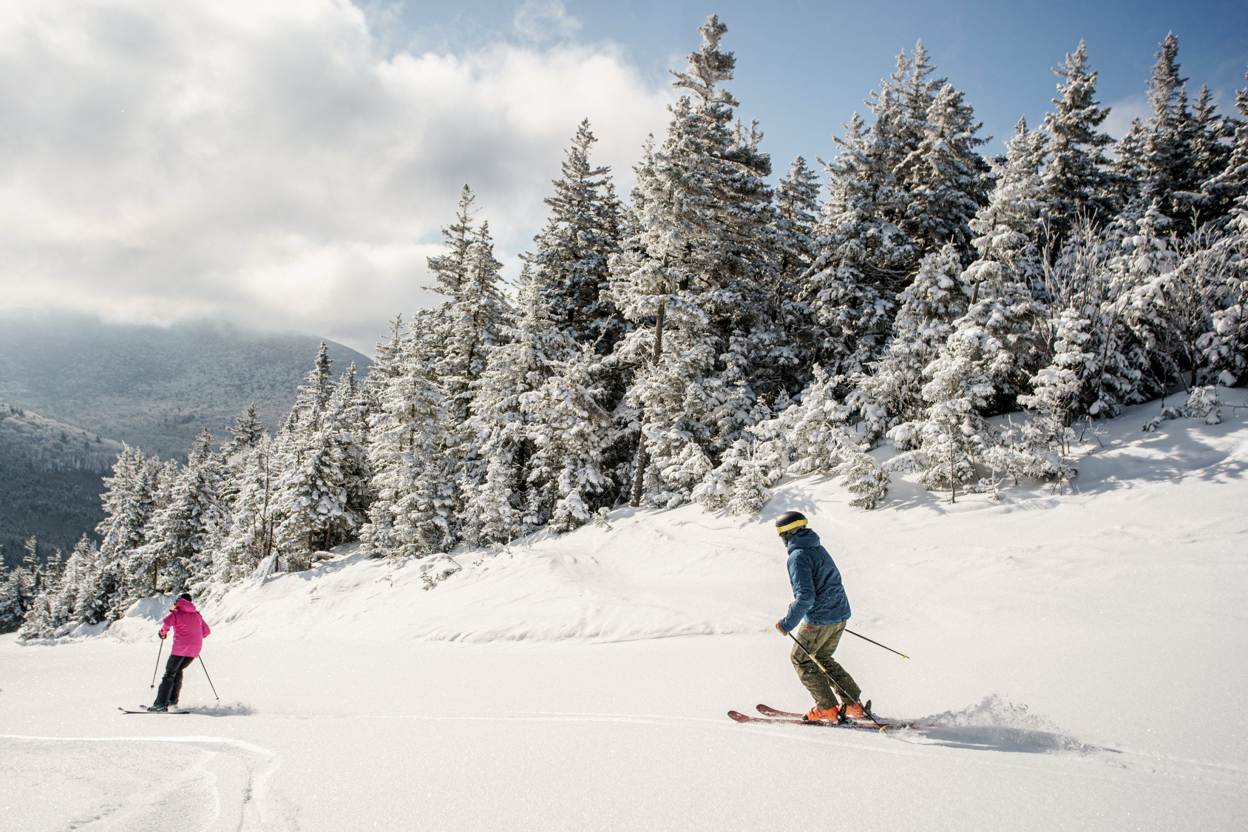 Two skiers descend the snowy slope on a sunny day at Bretton Woods.