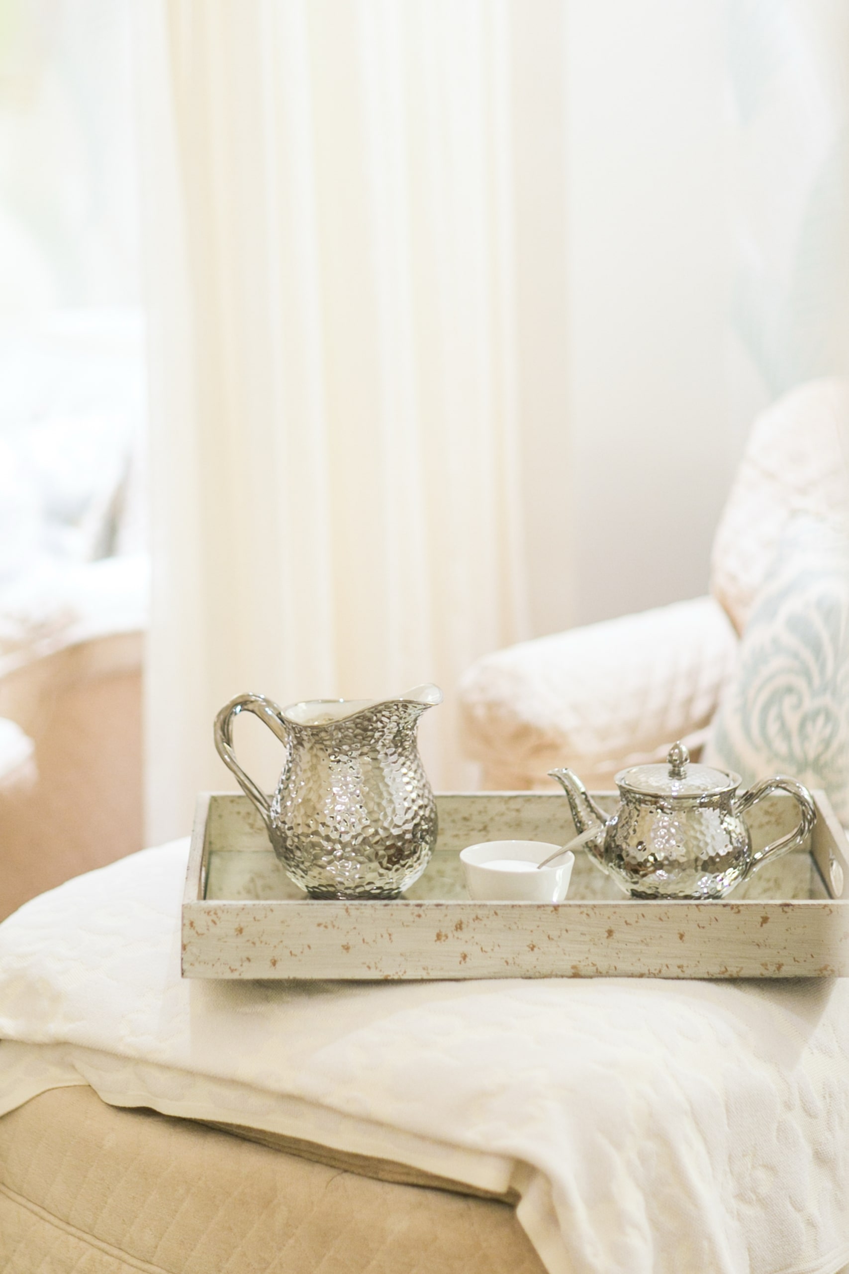 A silver teapot, creamer, and sugar bowl on a tray atop a cushioned chair at the spa at Mount Washington Resort and Spa.