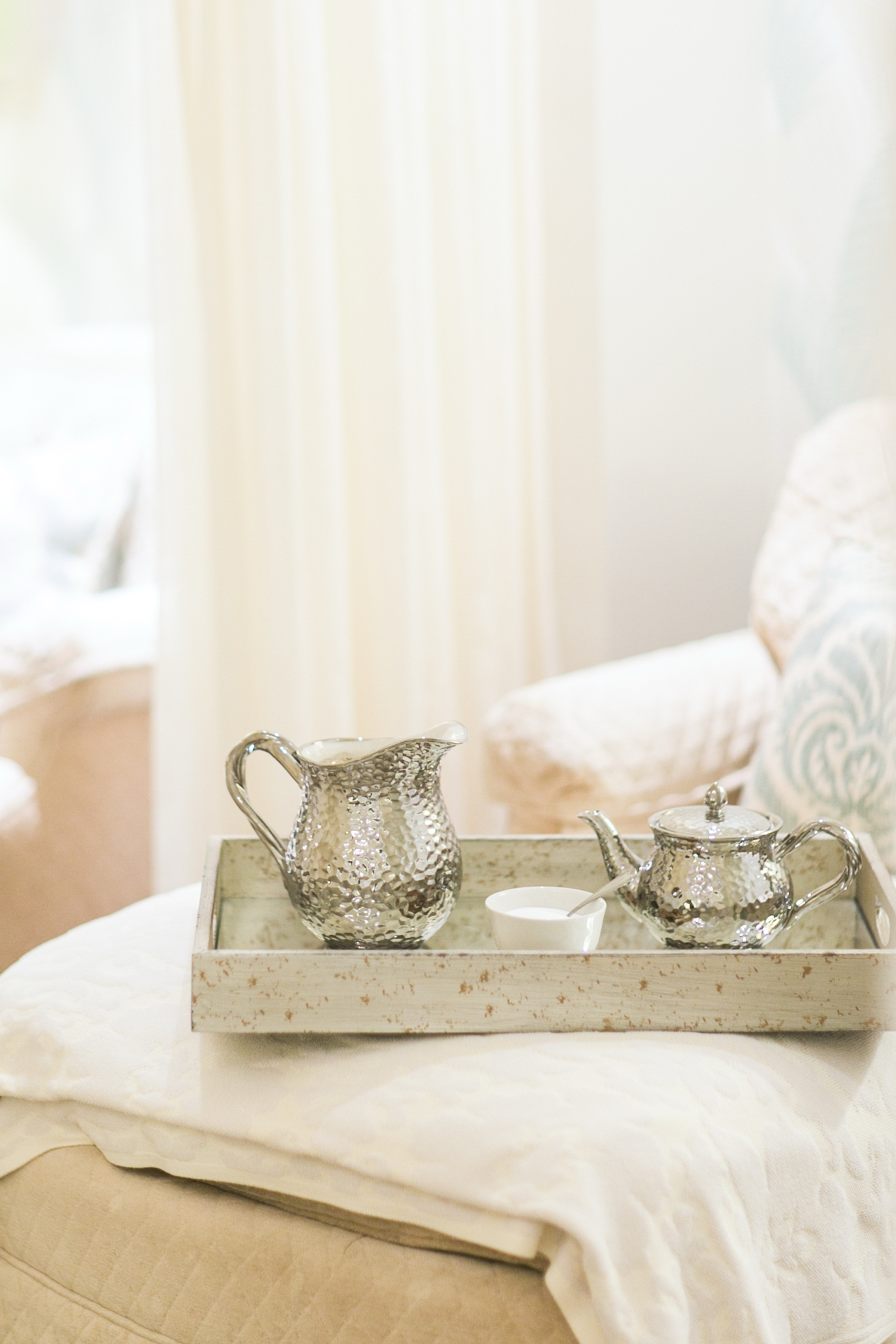 A silver teapot, creamer, and sugar bowl on a tray atop a cushioned chair at the spa at Mount Washington Resort and Spa.