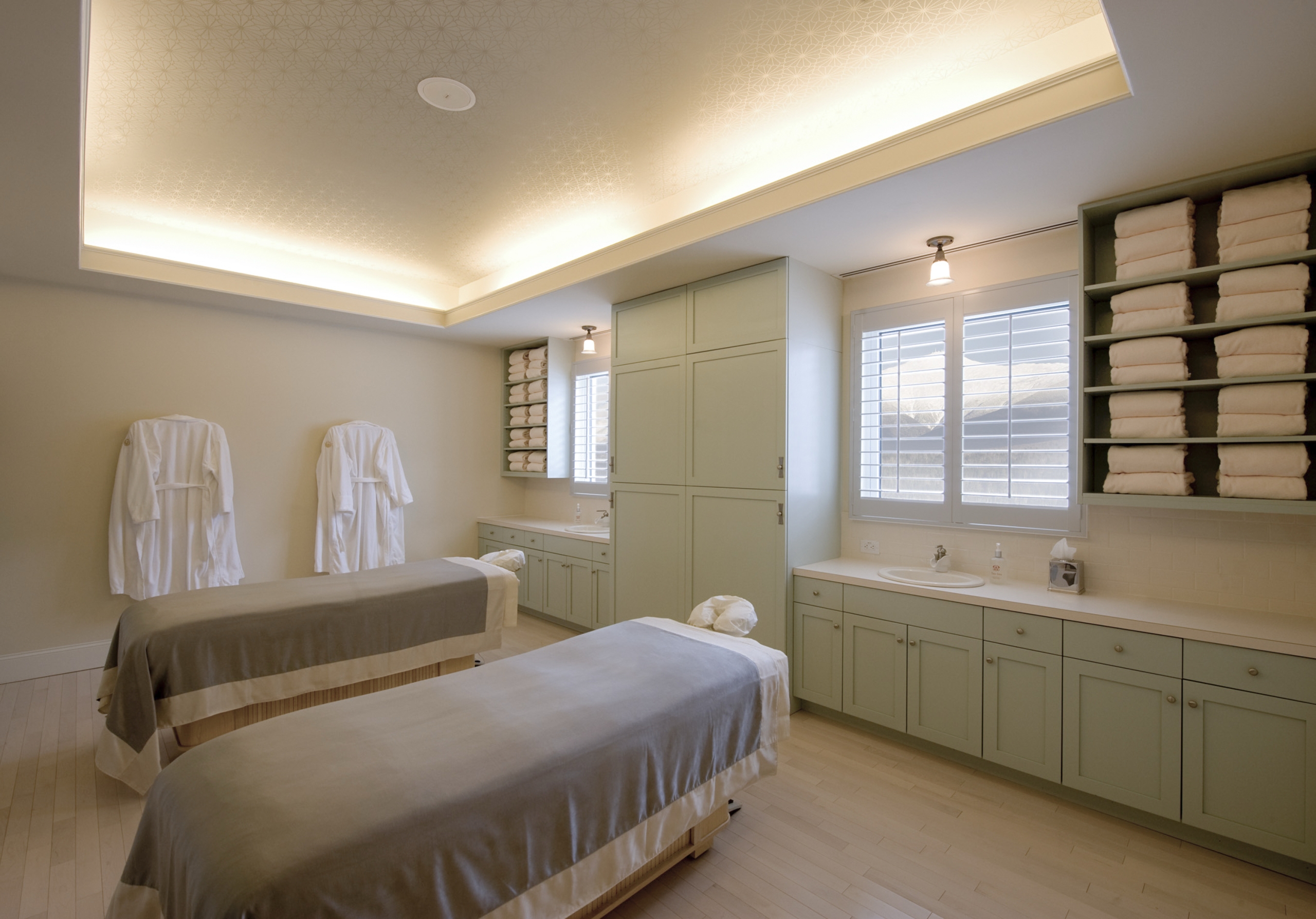 Elegant spa treatment room with two massage tables, soft lighting, and neatly stacked towels along the walls at Mount Washington Resort and Spa.