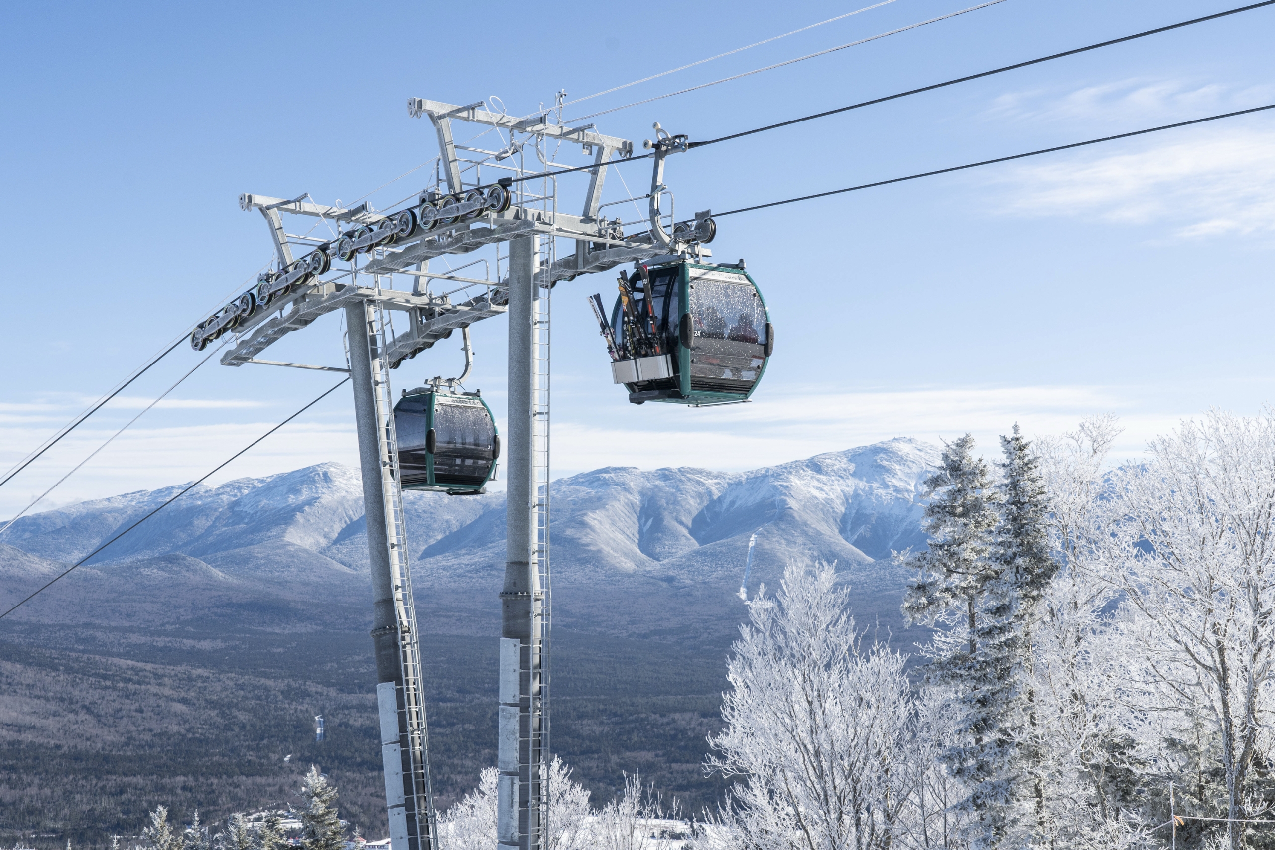 Two ski gondolas carry riders up a snowy mountain at Bretton Woods.