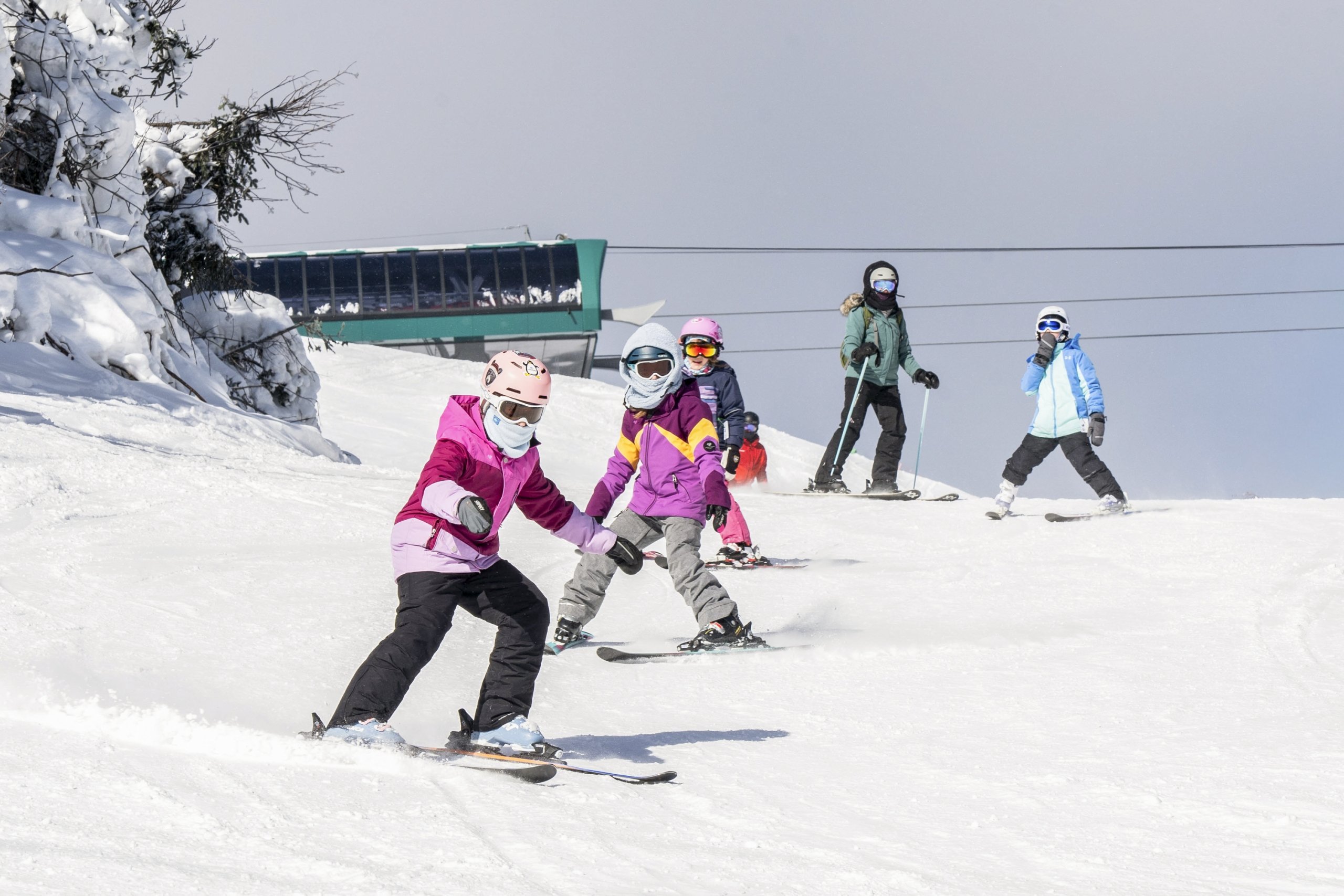 Children skiing down a snowy mountain slope on a sunny winter day at Bretton Woods.
