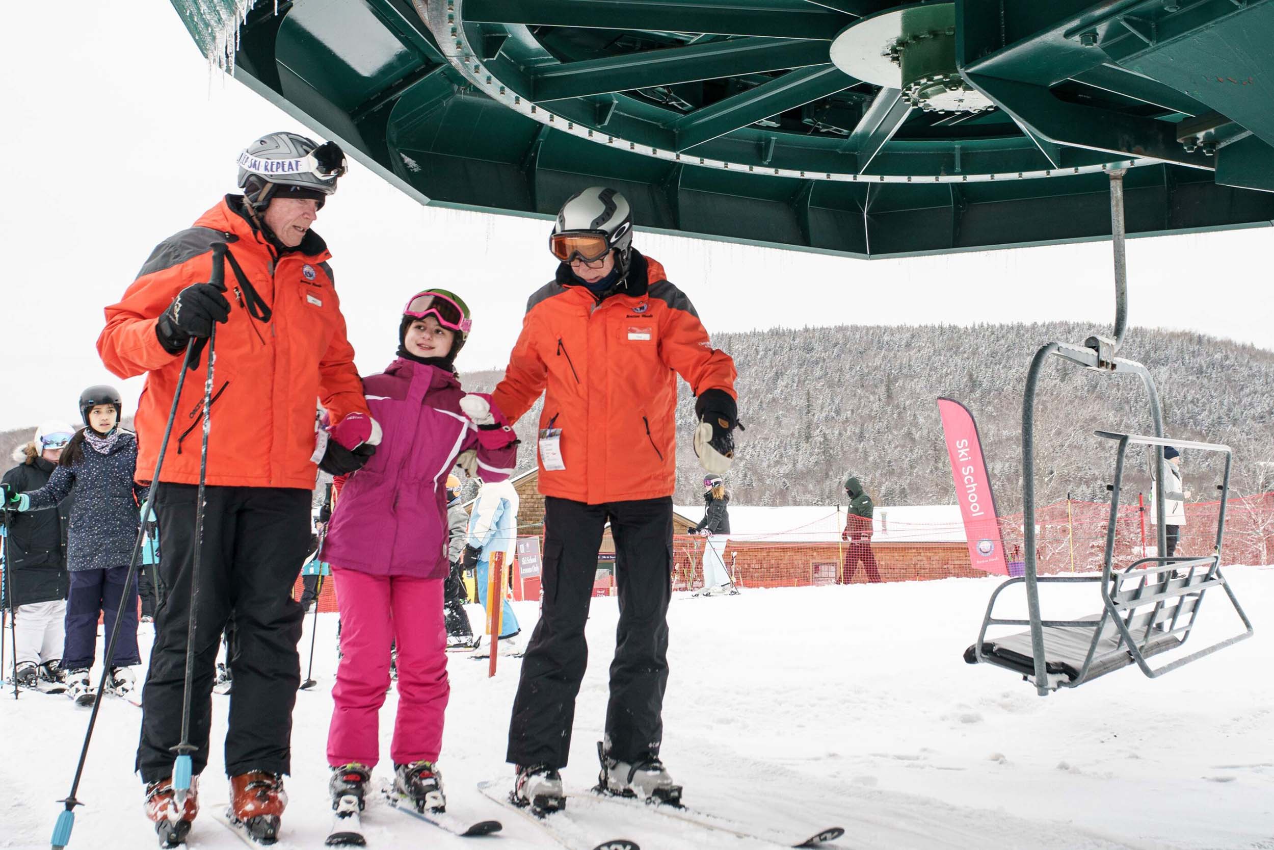 Two ski instructors help a student off a chair lift at Bretton Woods.