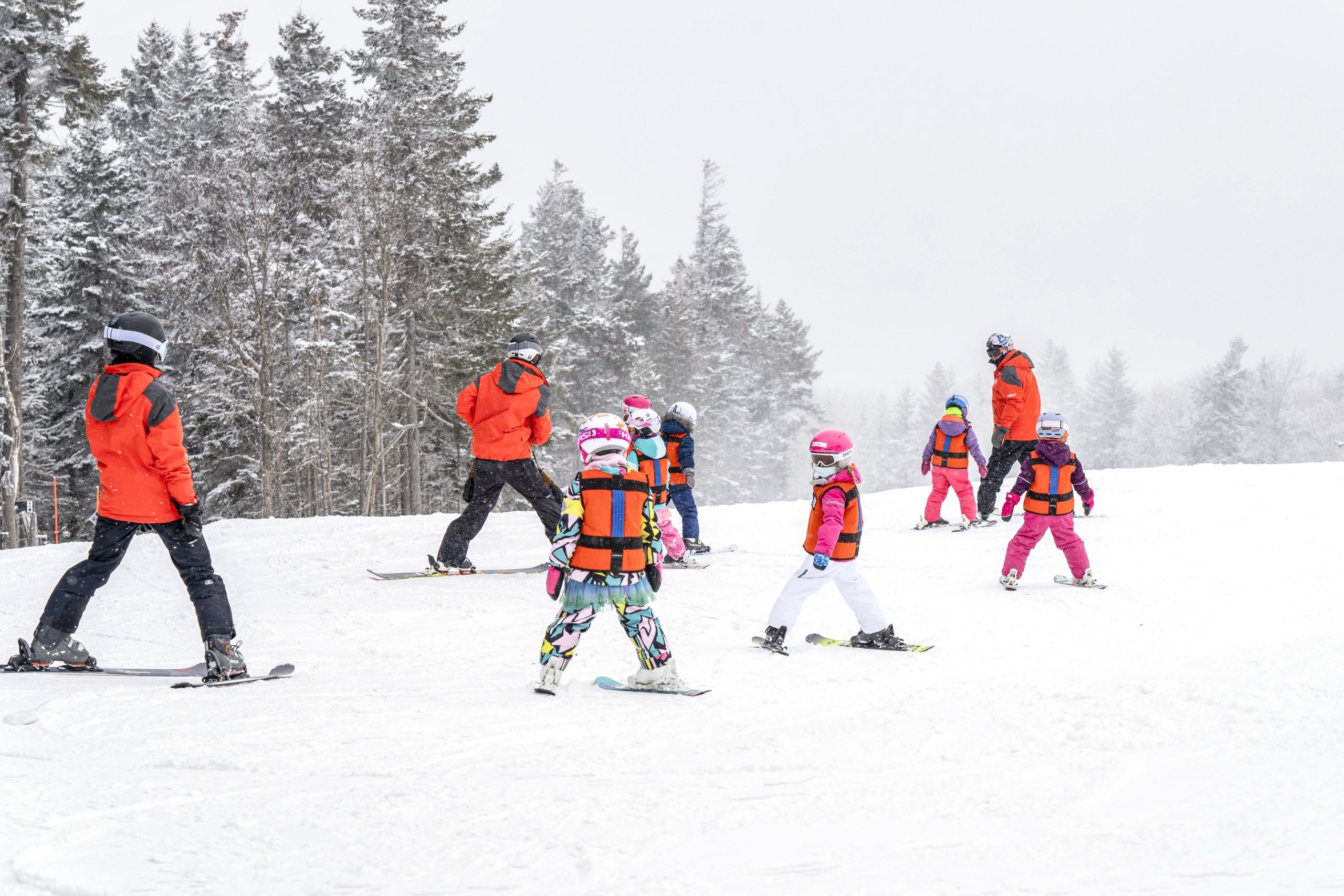 Group of young children in taking a ski lesson on a snowy slope, guided by instructors at Bretton Woods.