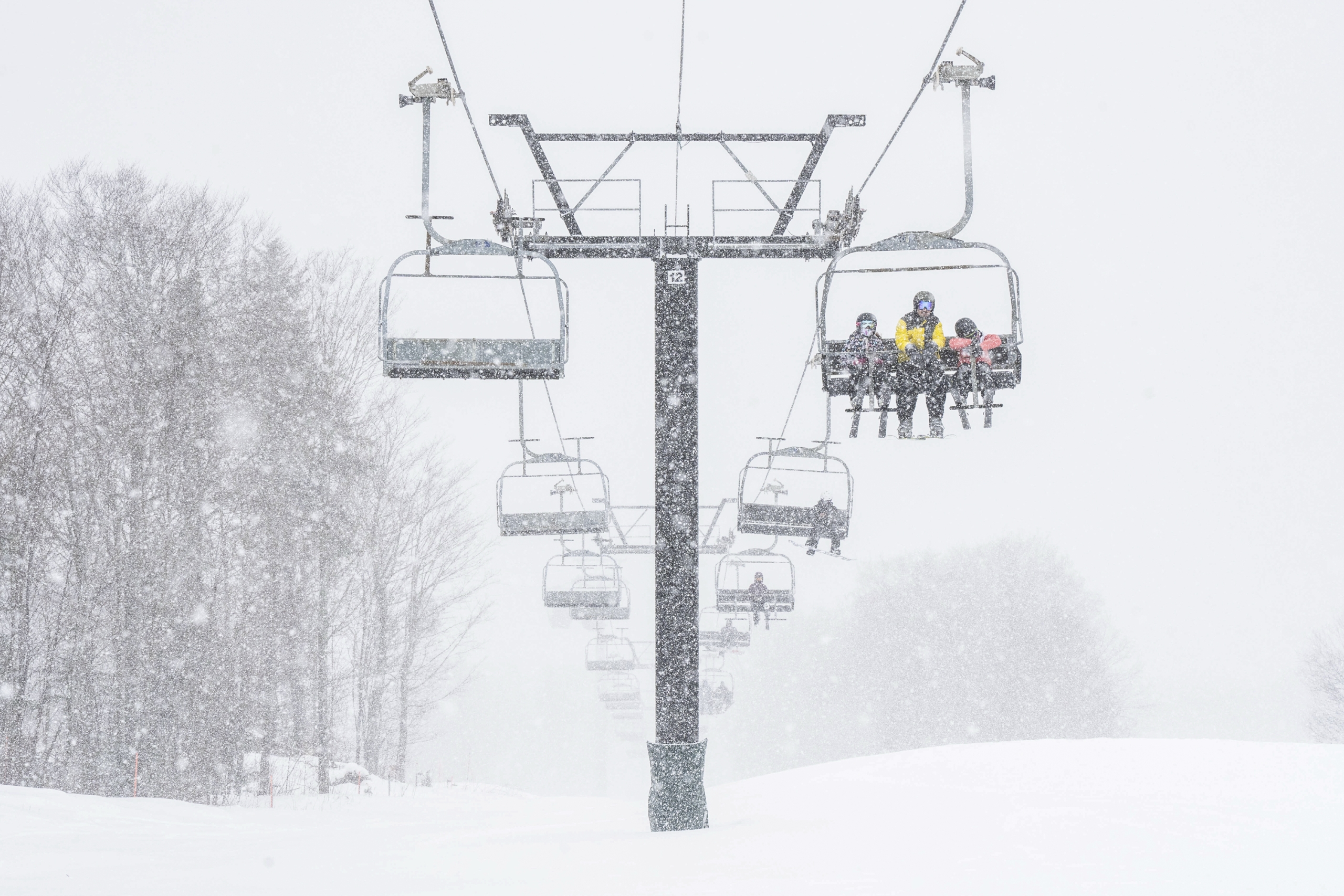 Skiers ride the chair lift down the mountain through a snowstorm at Bretton Woods.
