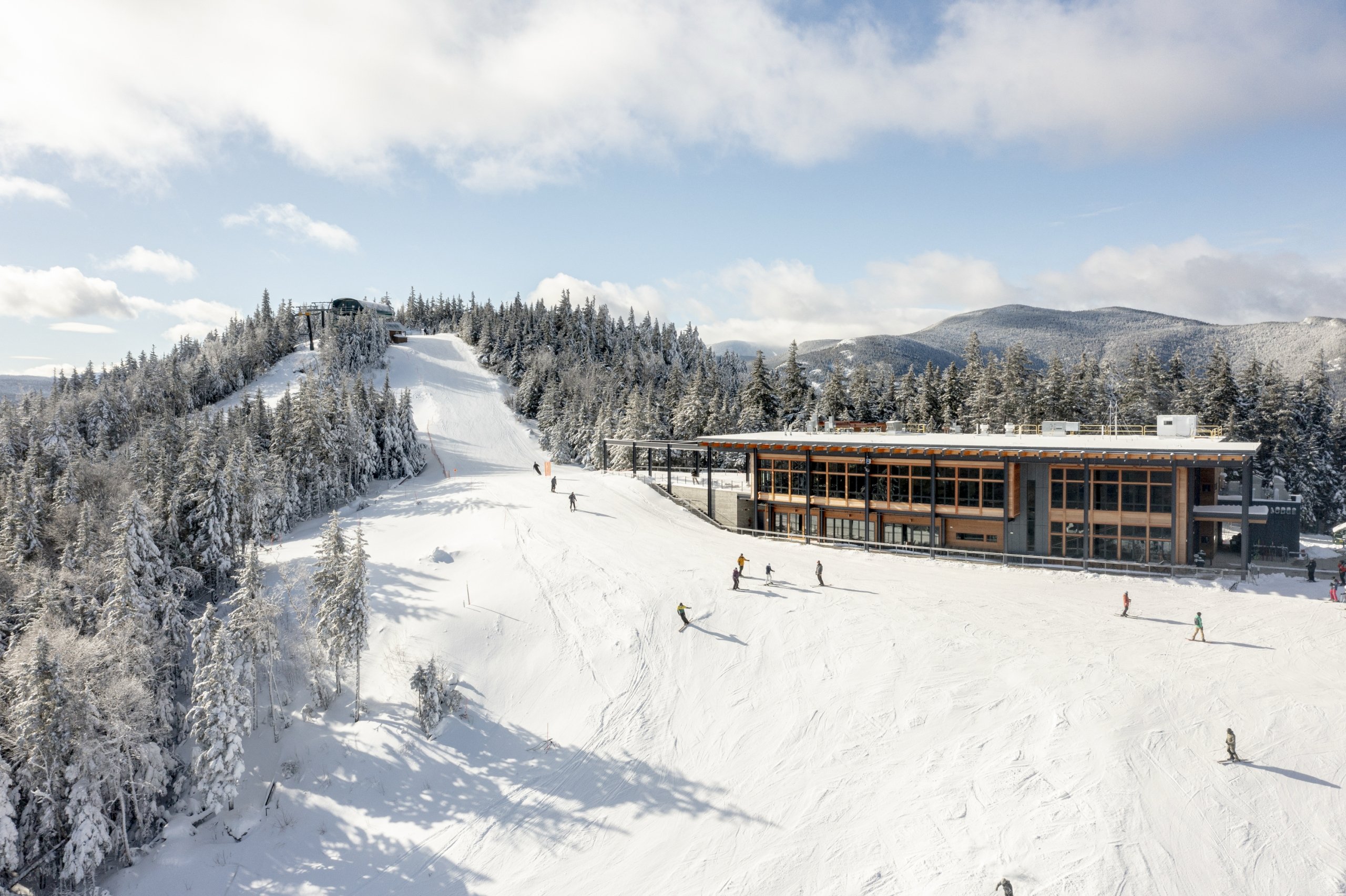 Skiers glide down a snowy slope near the lodge at Bretton Woods.