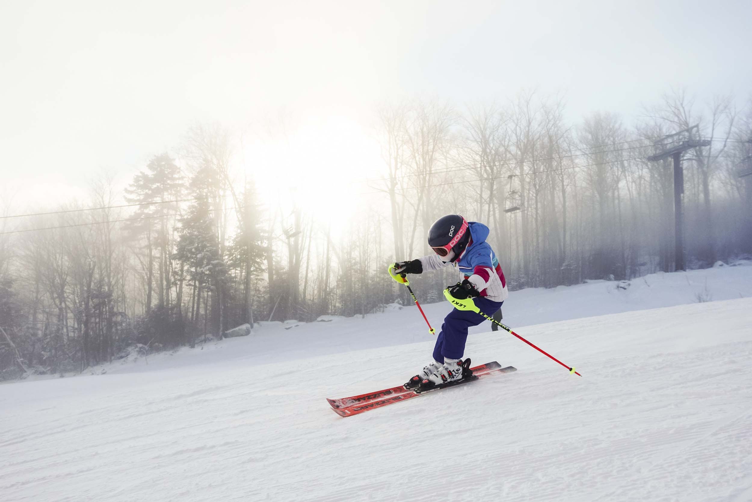 A child ski racer speeds down the hill with a misty sky at Bretton Woods.