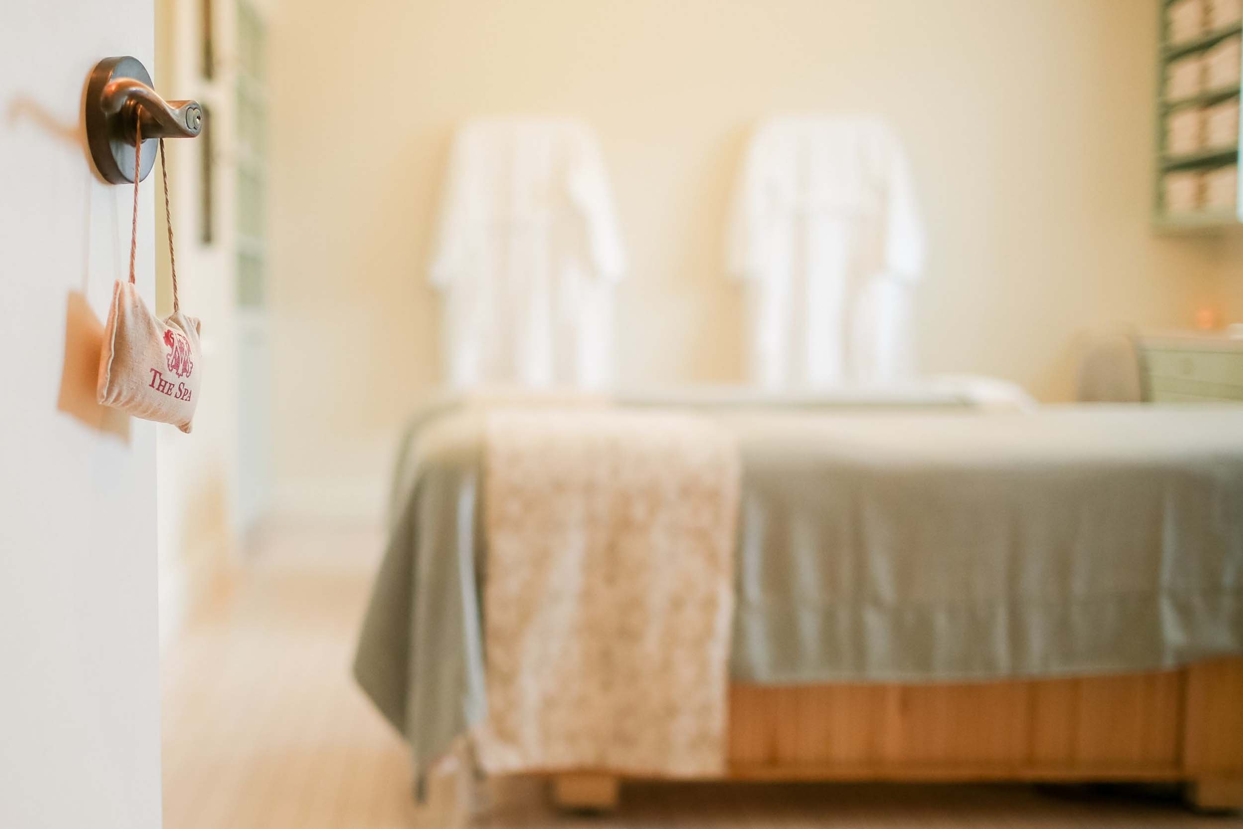 Softly lit spa room with a massage table, two robes, and a small pillow sign hanging on the door handle at Mount Washington Resort and Spa.