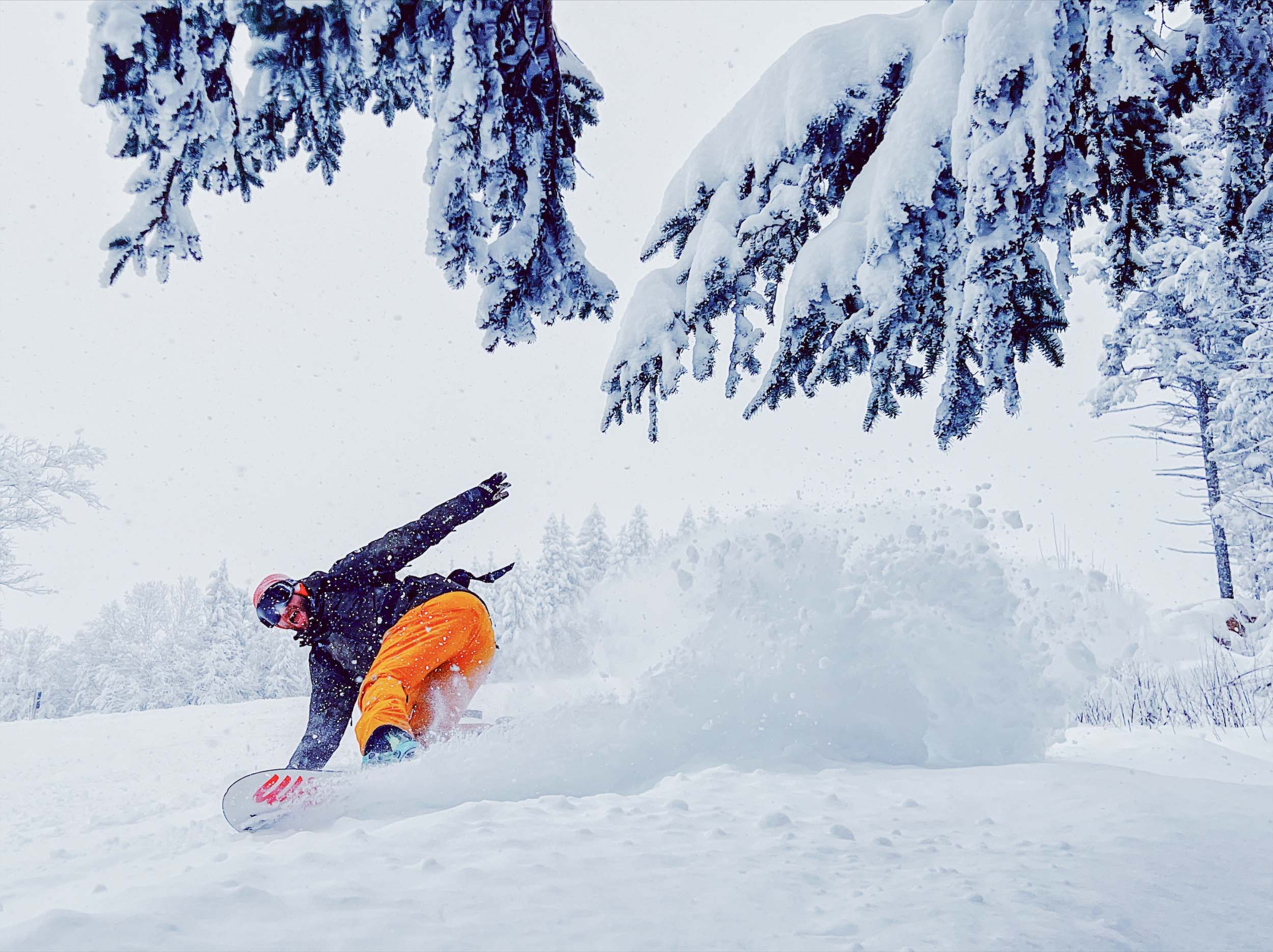 A snowboarder pivots, kicking up powdery snow in the air, while gliding down the mountain at Bretton Woods.