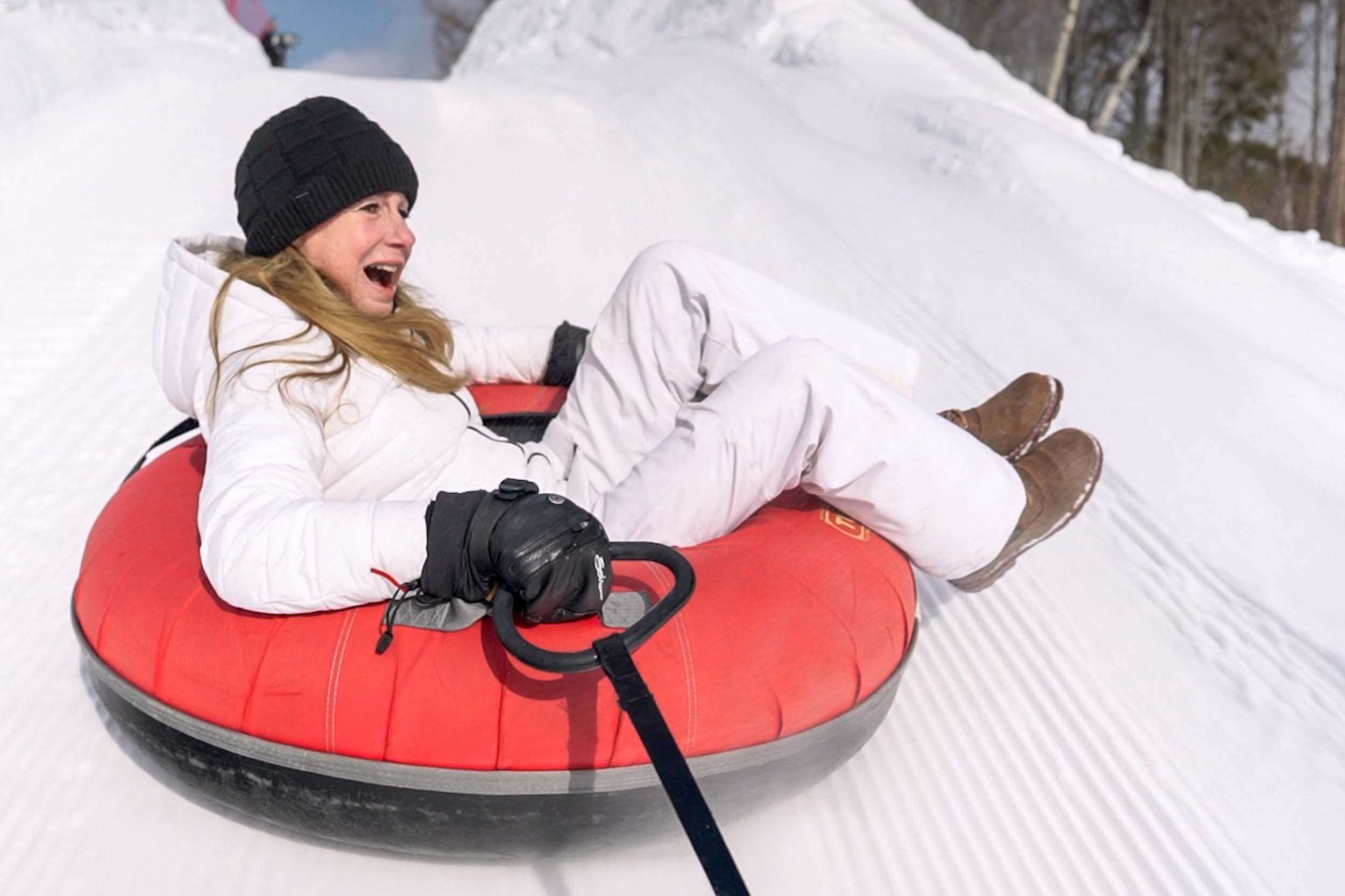 A woman enjoys riding down the hill on a snow tube at Mount Washington Resort and Spa.