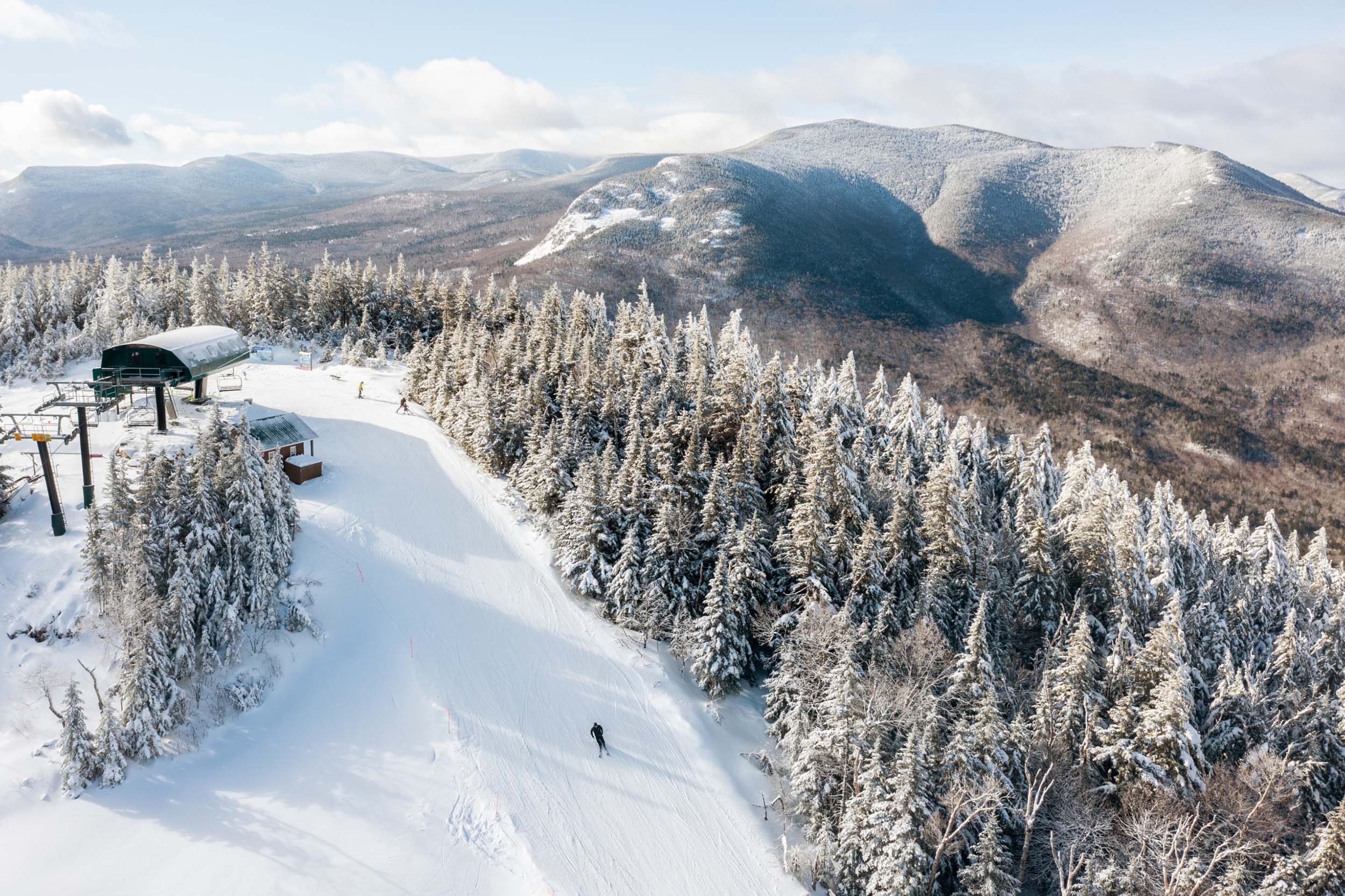 Aerial view of a ski trail amongst a forest of trees and snow-capped mountains at Bretton Woods.