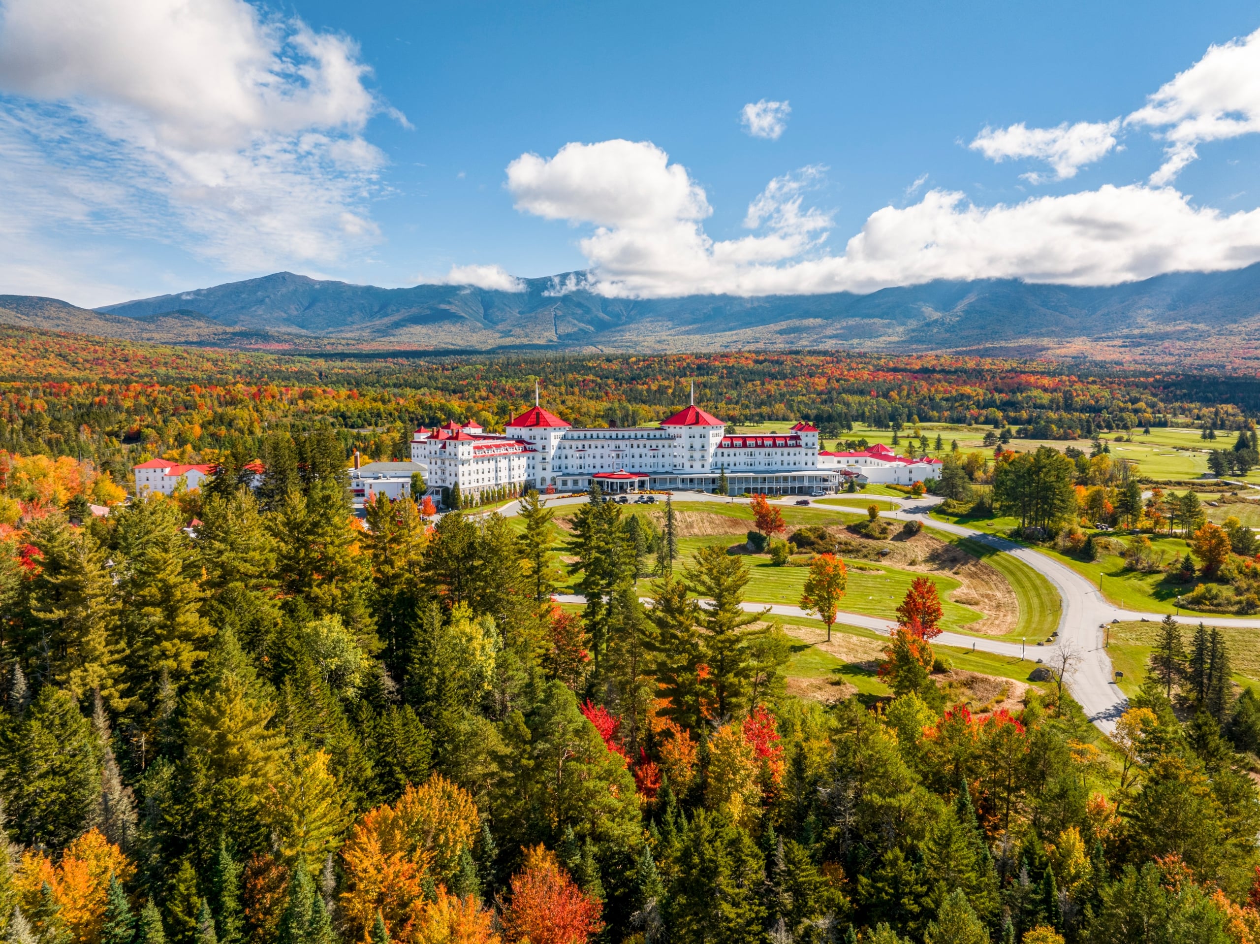 Mount Washington Resort and Spa sits at the bottom of a mountain surrounded by a lush forest of trees in vibrant fall colours.