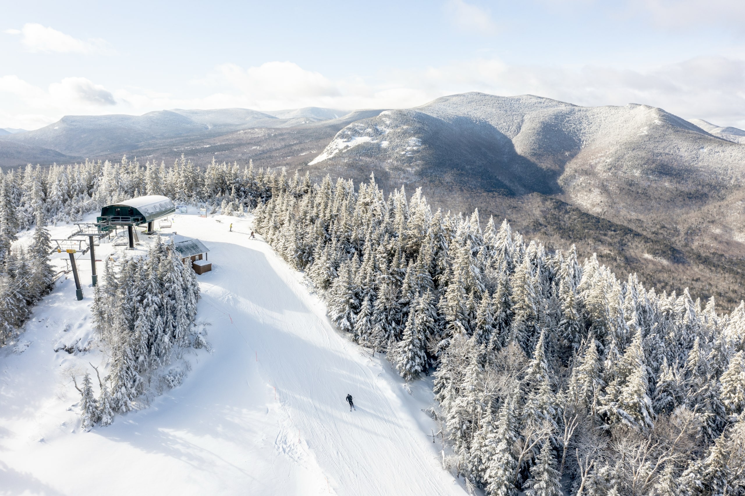 Aerial view of a ski trail amongst a forest of trees and snow-capped mountains at Bretton Woods.