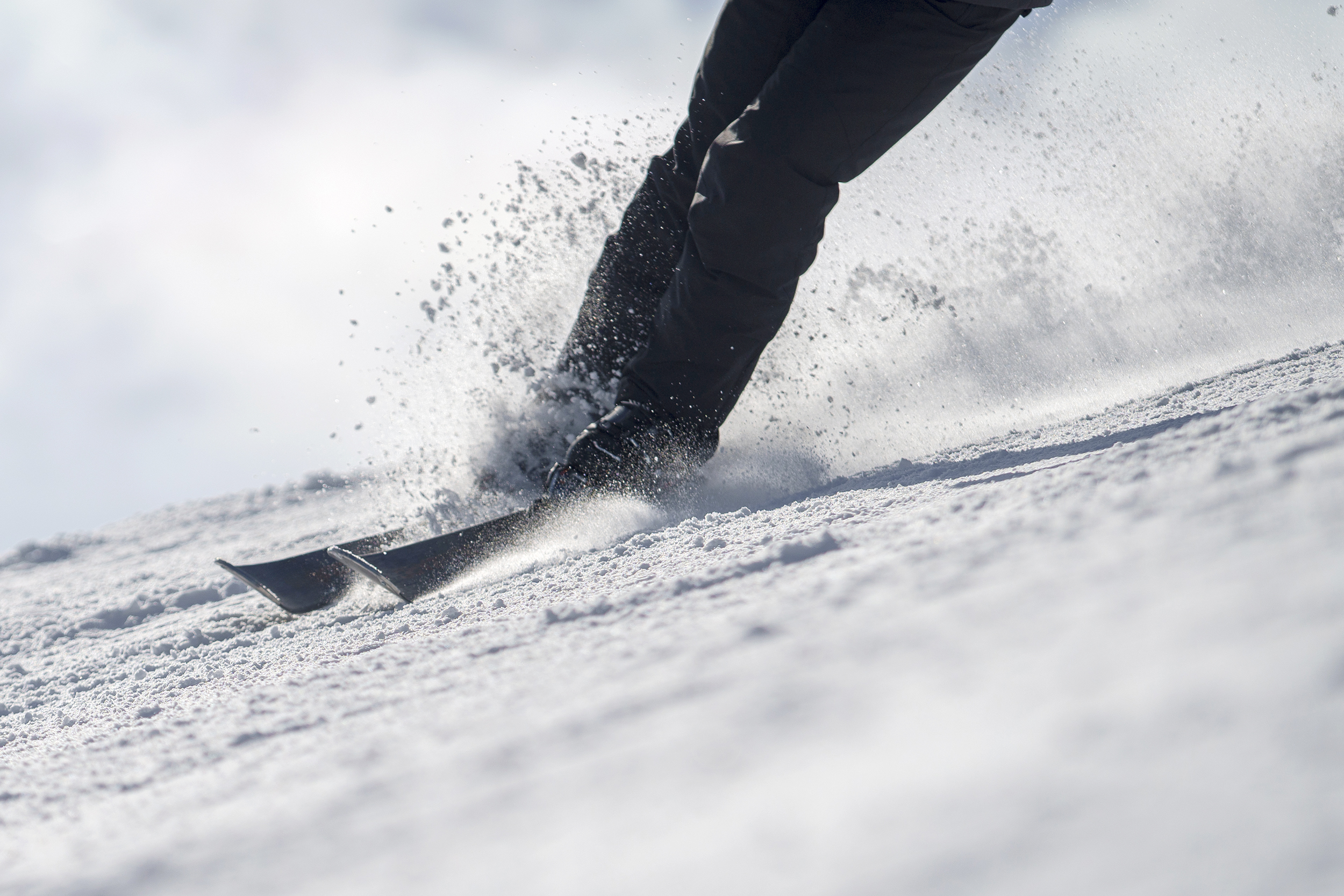 Close-up photo of skier carving through snow